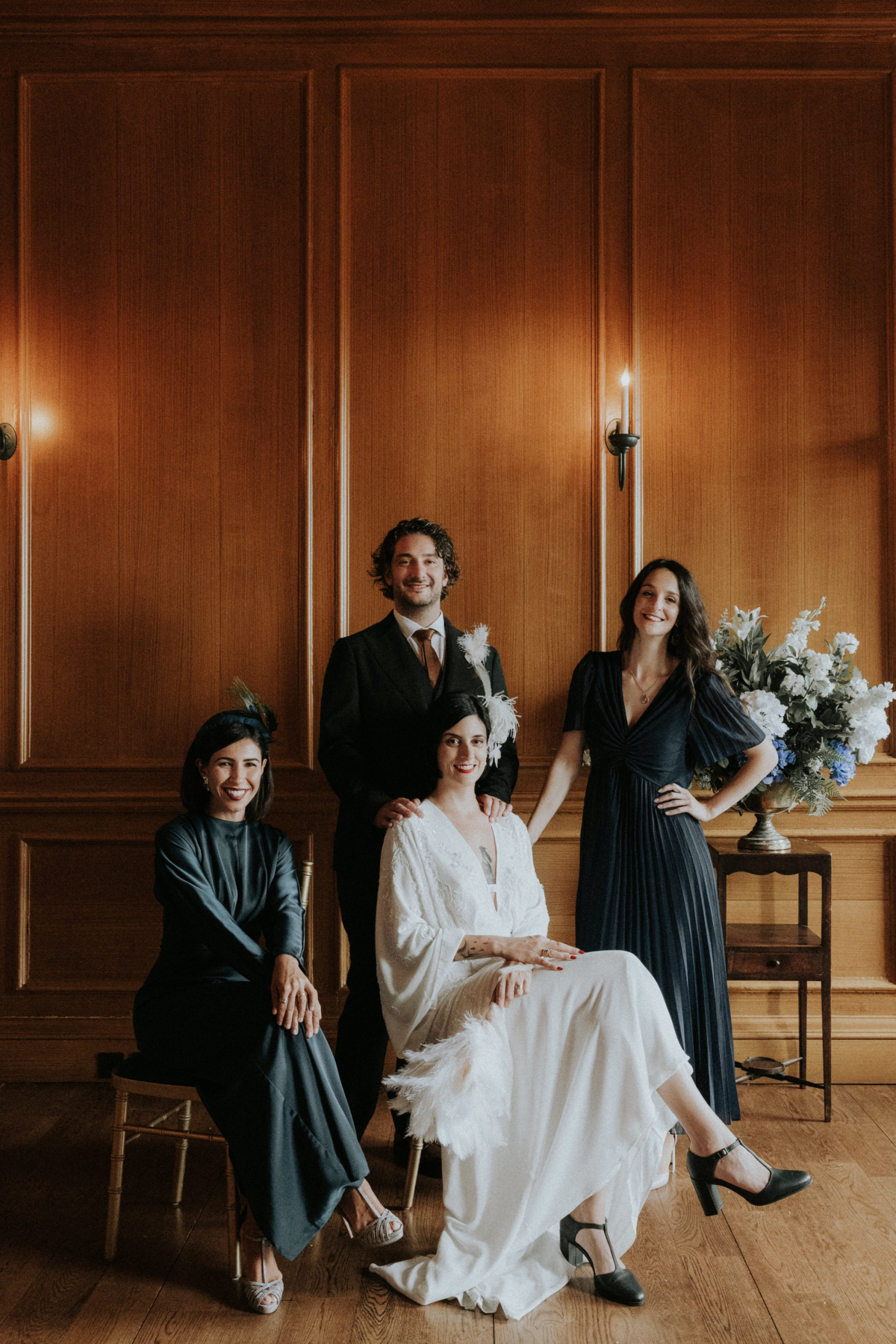 A Chic, Modern & Intimate Edinburgh City Wedding with an ASOS Dress 26 Seated bride in an ASOS wedding dress and black t-bar block heel shoes. She is surrounded by her bridesmaids in black dresses and her groom. Riddles Court wedding in Edinburgh. Bernadeta Kupiec Photography.