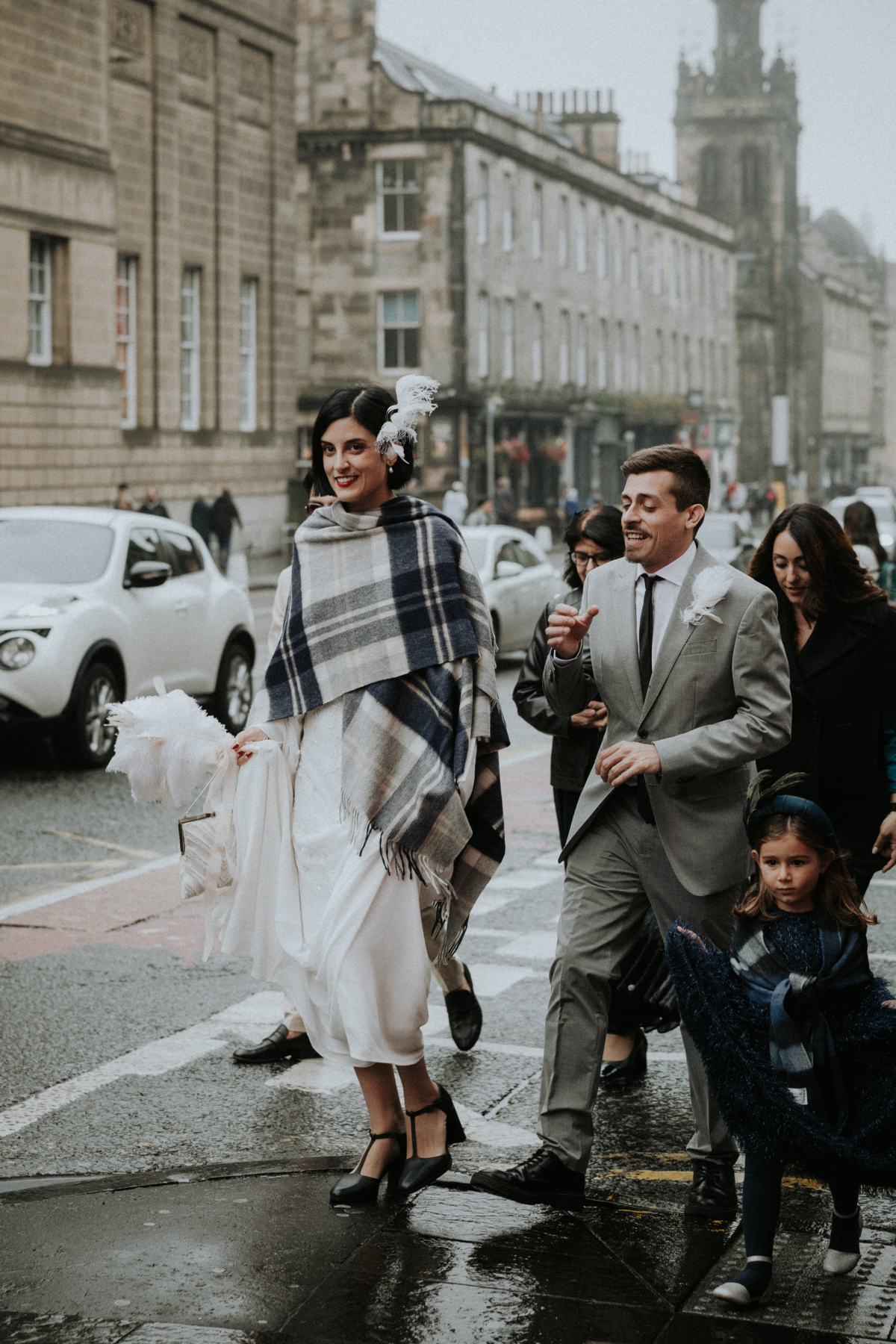 A Chic, Modern & Intimate Edinburgh City Wedding with an ASOS Dress 20 Bride walking through the streets of Edinburgh on her wedding day. She wears a tartan blanket over her ASOS wedding dress, and t-bar black block heel shoes. Bernadeta Kupiec Photography.