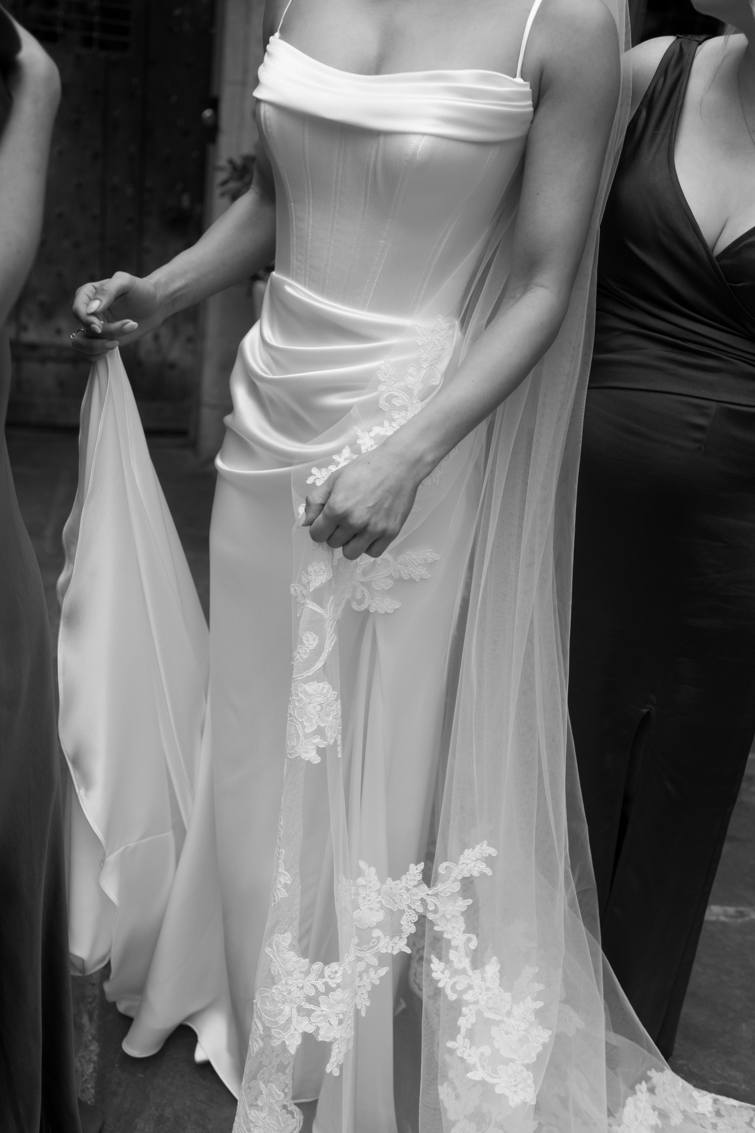 A Classy & Modern City Wedding at the Bodleian Library With Jamaican-Guyanese Heritage 30 Close-up of a modern bridal gown with a structured corset bodice, draped satin skirt and detailed floral embroidery on the veil, in an elegant black-and-white frame.