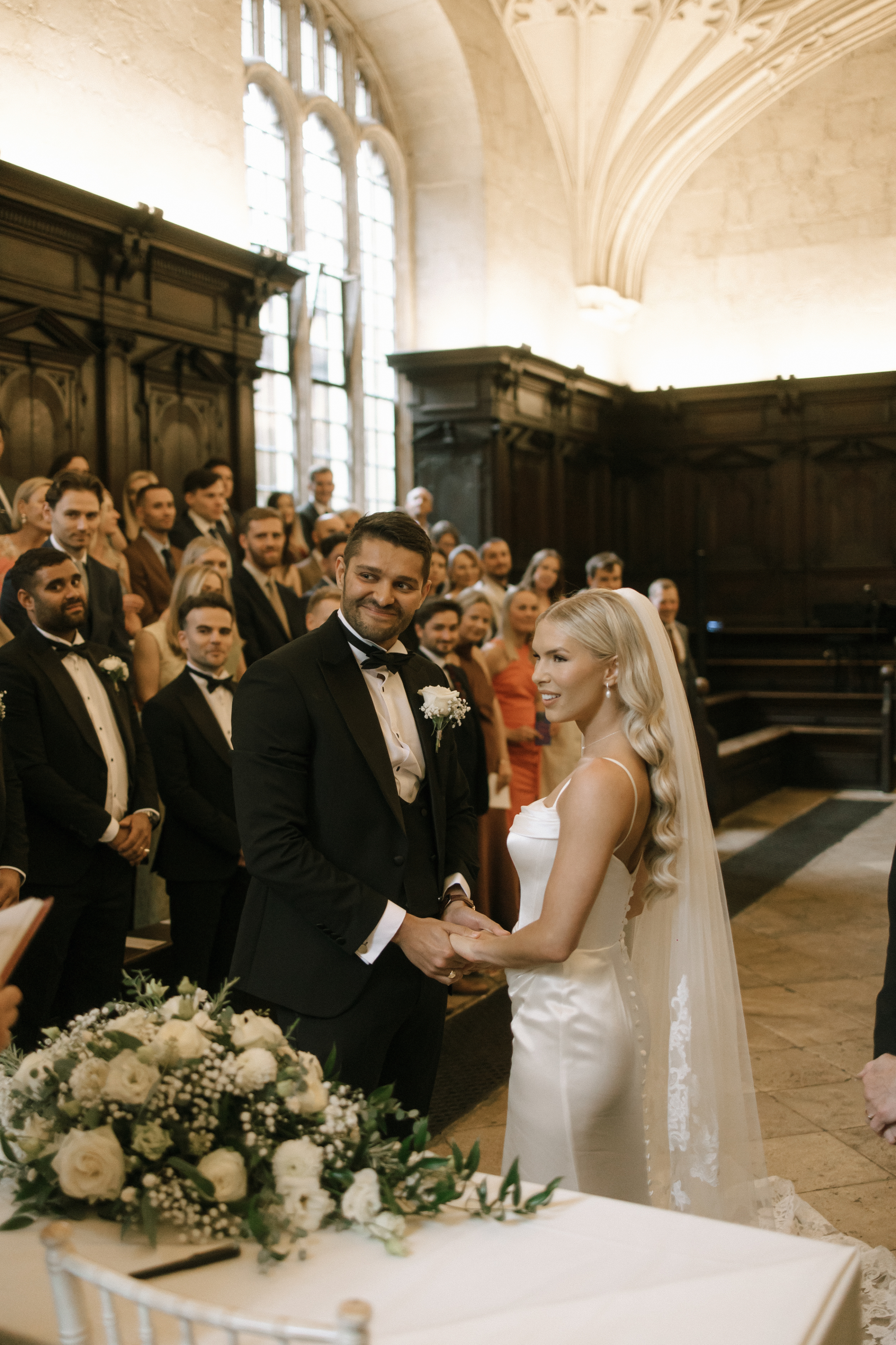 The couple exchanges vows in the intimate setting of Oriel College Chapel, adorned with classic decor.