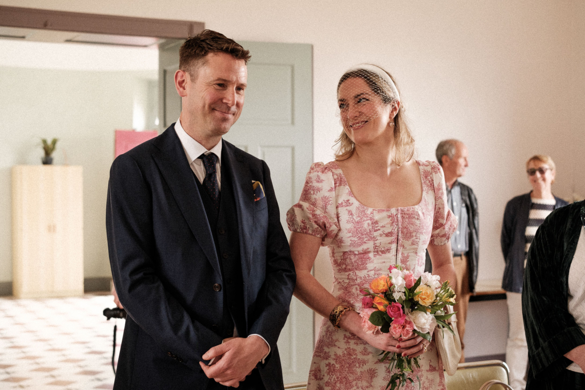 A quiet, tender moment during Constance and Nial’s civil ceremony in the village town hall. Constance wore a romantic two-piece by Annina Dirndl and held a garden-style bouquet of seasonal spring blooms. Proof that tiny weddings can still be full of feeling.