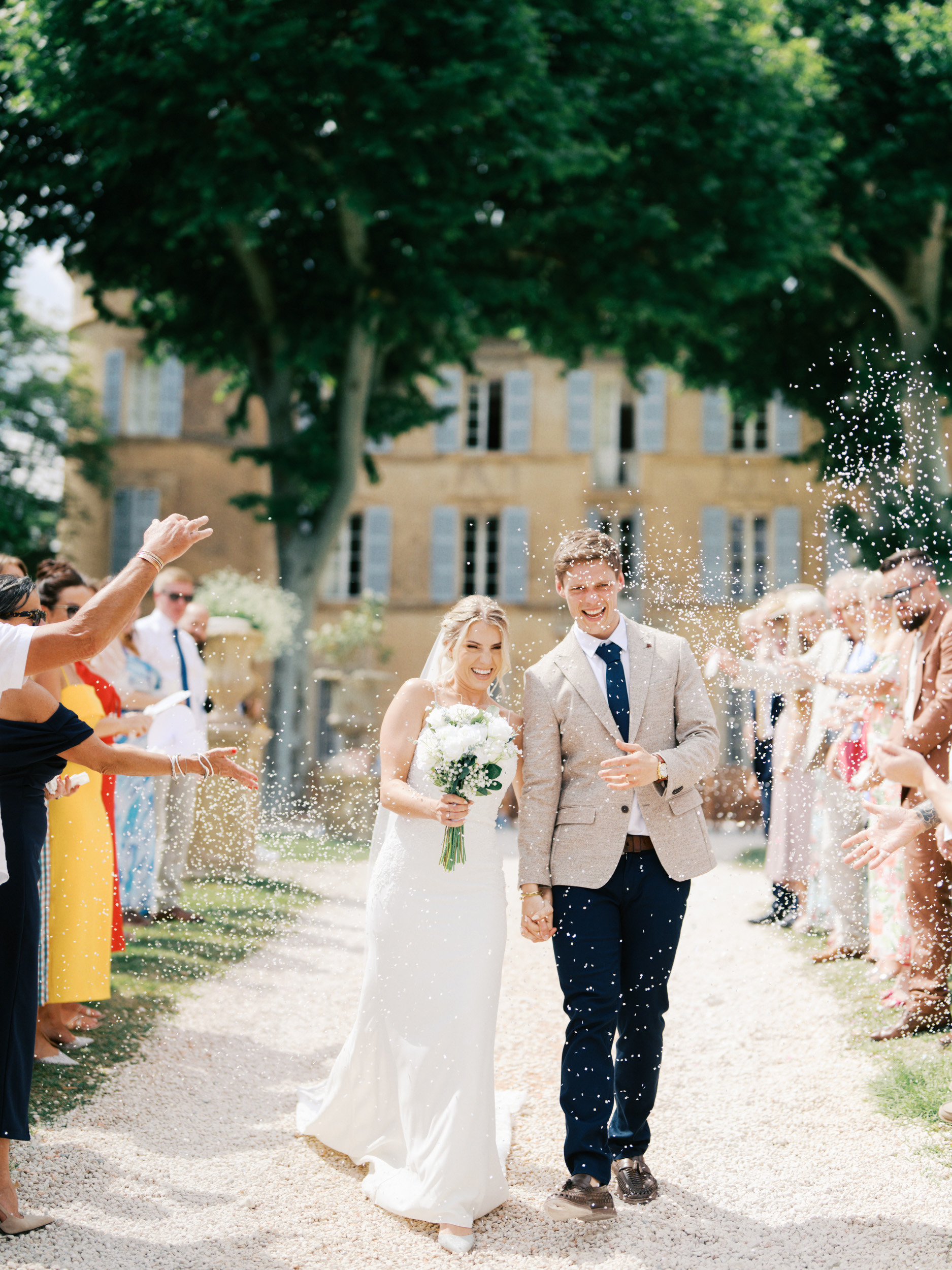 An Elegant Modern Wedding at Chateau de Robernier 66 Bride and groom in a confetti shower at Chateau de Robernier in Provence, South of France.