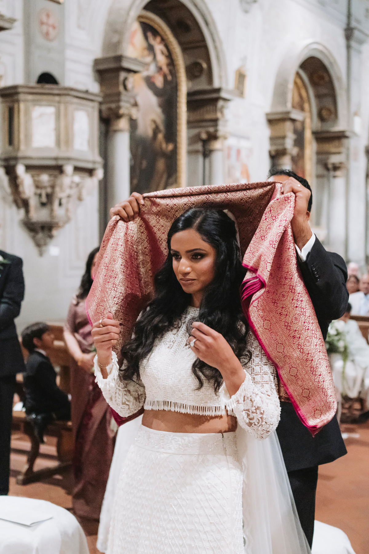 An Elegant Fusion of Indian Tradition and Italian Beauty 77 Modern Indian bride undergoing a tying of the Thali' Indian tradition during here wedding ceremony. A manthrakodi is being tied gently around her neck.