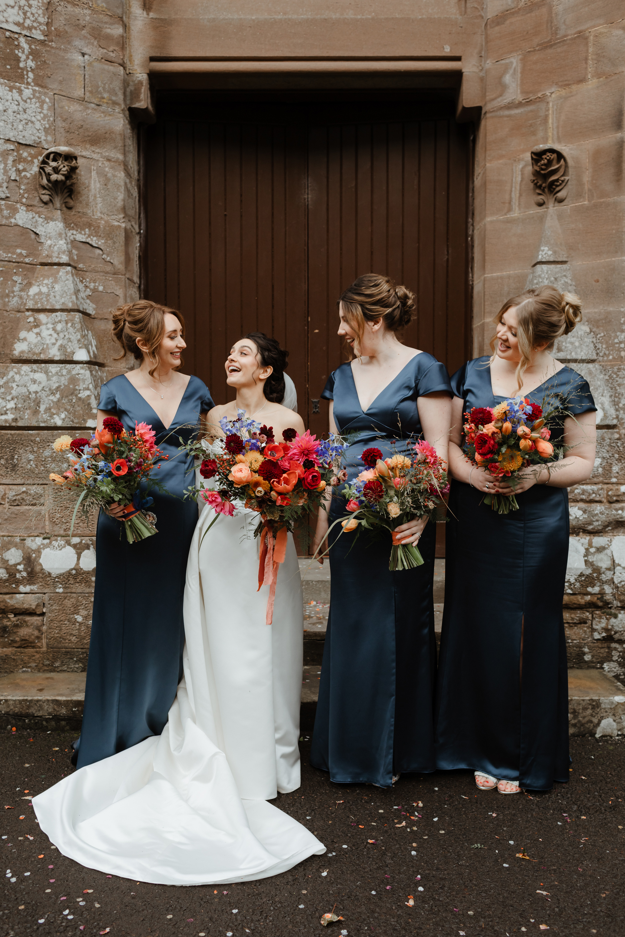 Savannah Miller Elegance for a Joyful Autumn Wedding at Drumtochty Castle 74 Bride in Savannah Miller and her bridesmaids in navy blue dresses. They all carry large colourful wedding bouquets.