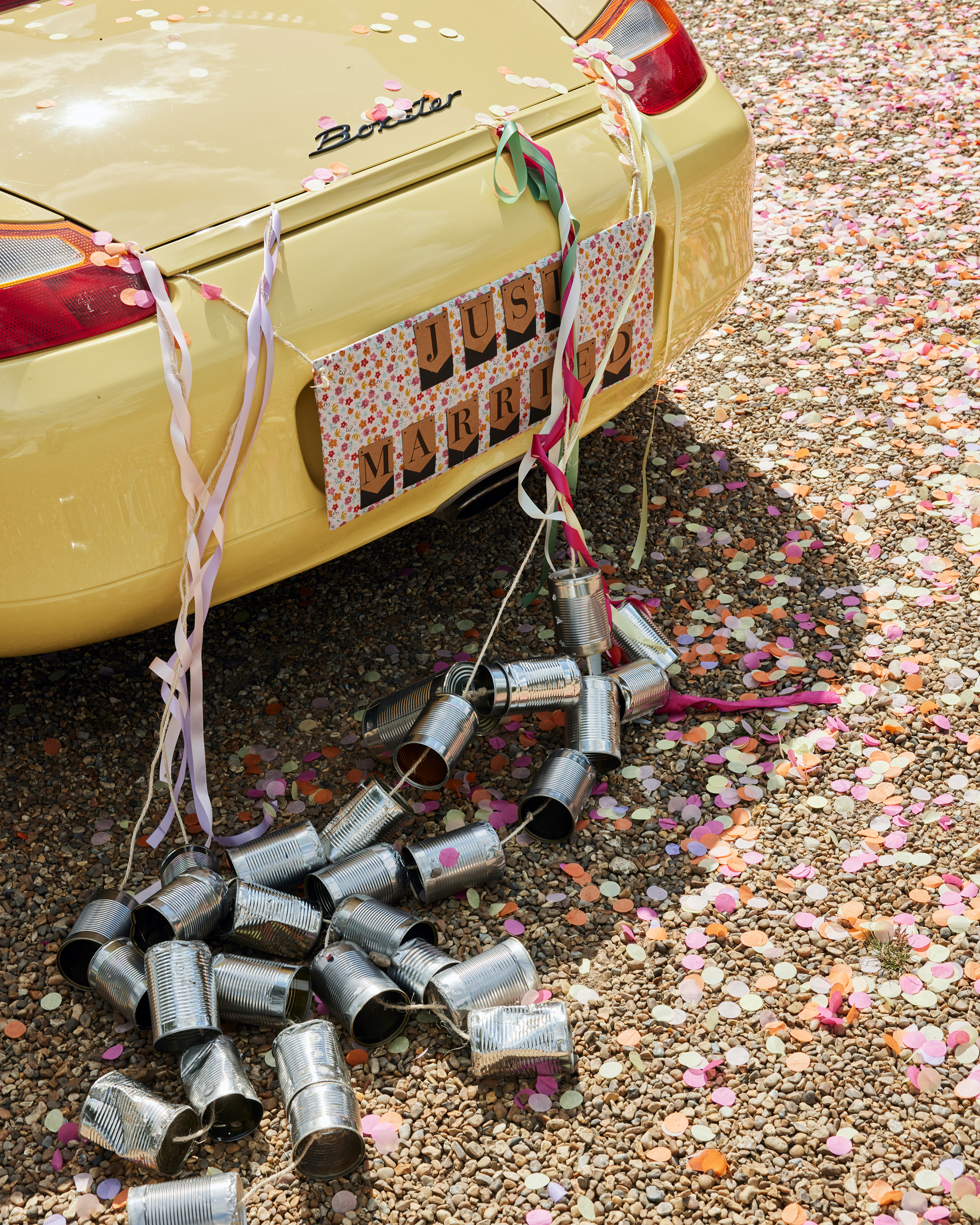 Alex in Emma Beaumont for her Ibiza & Disco Inspired Wedding at Wilderness Reserve 47 Yellow sports car on a wedding day with traditional tin cans and ribbons tied to the back.