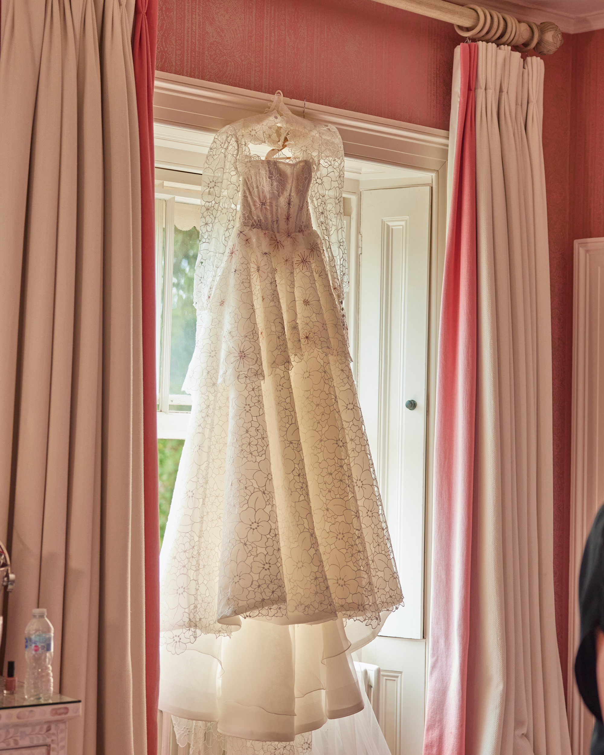Alex in Emma Beaumont for her Ibiza & Disco Inspired Wedding at Wilderness Reserve 35 Emma Beaumont Atelier lace peplum wedding dress hanging in the window.