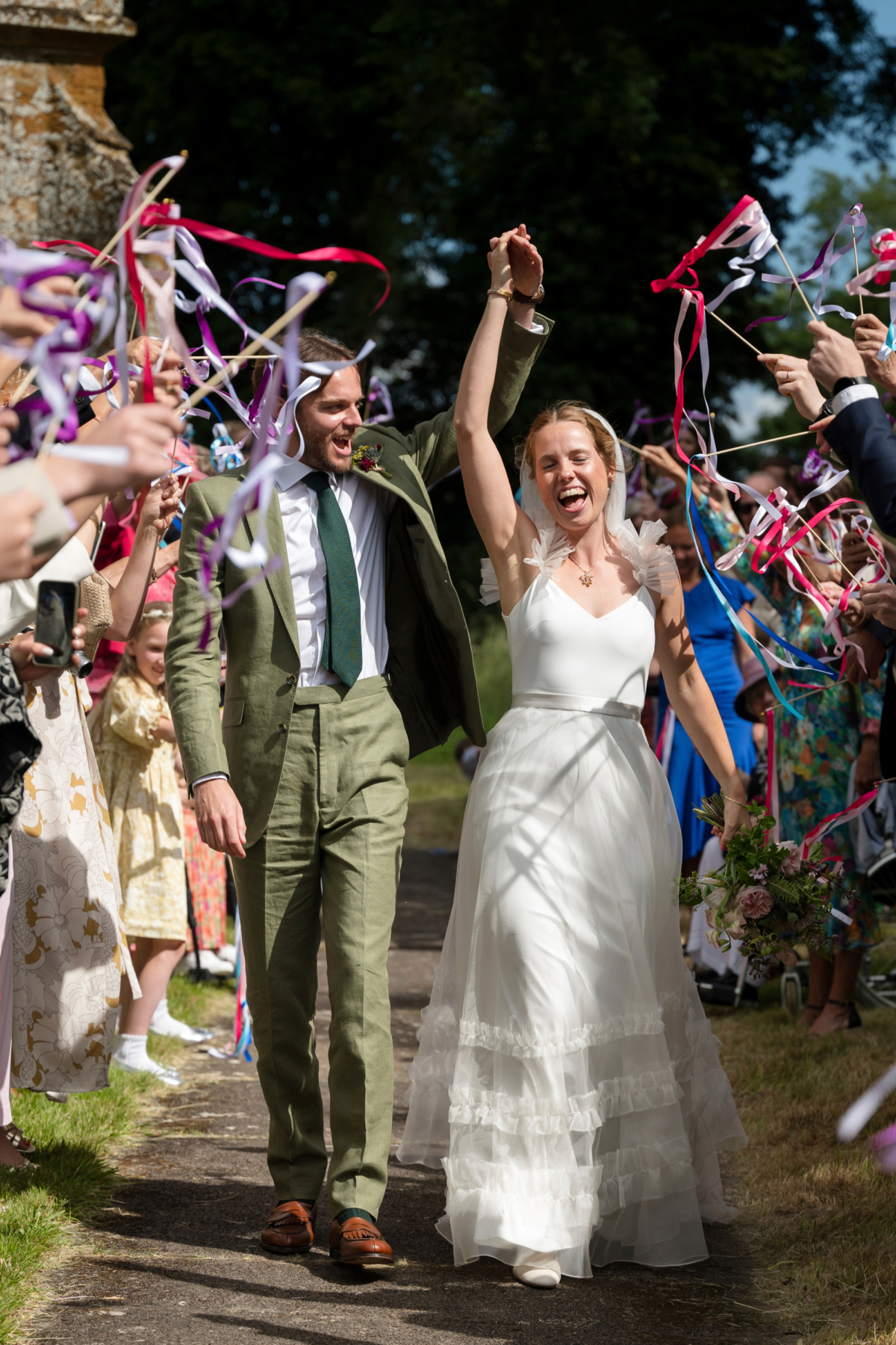 A Teepee & Bell Tent Wedding in Greens & Buttermilk Yellow 17 Bride and groom exiting to a tunnel of ribbons being twirled.