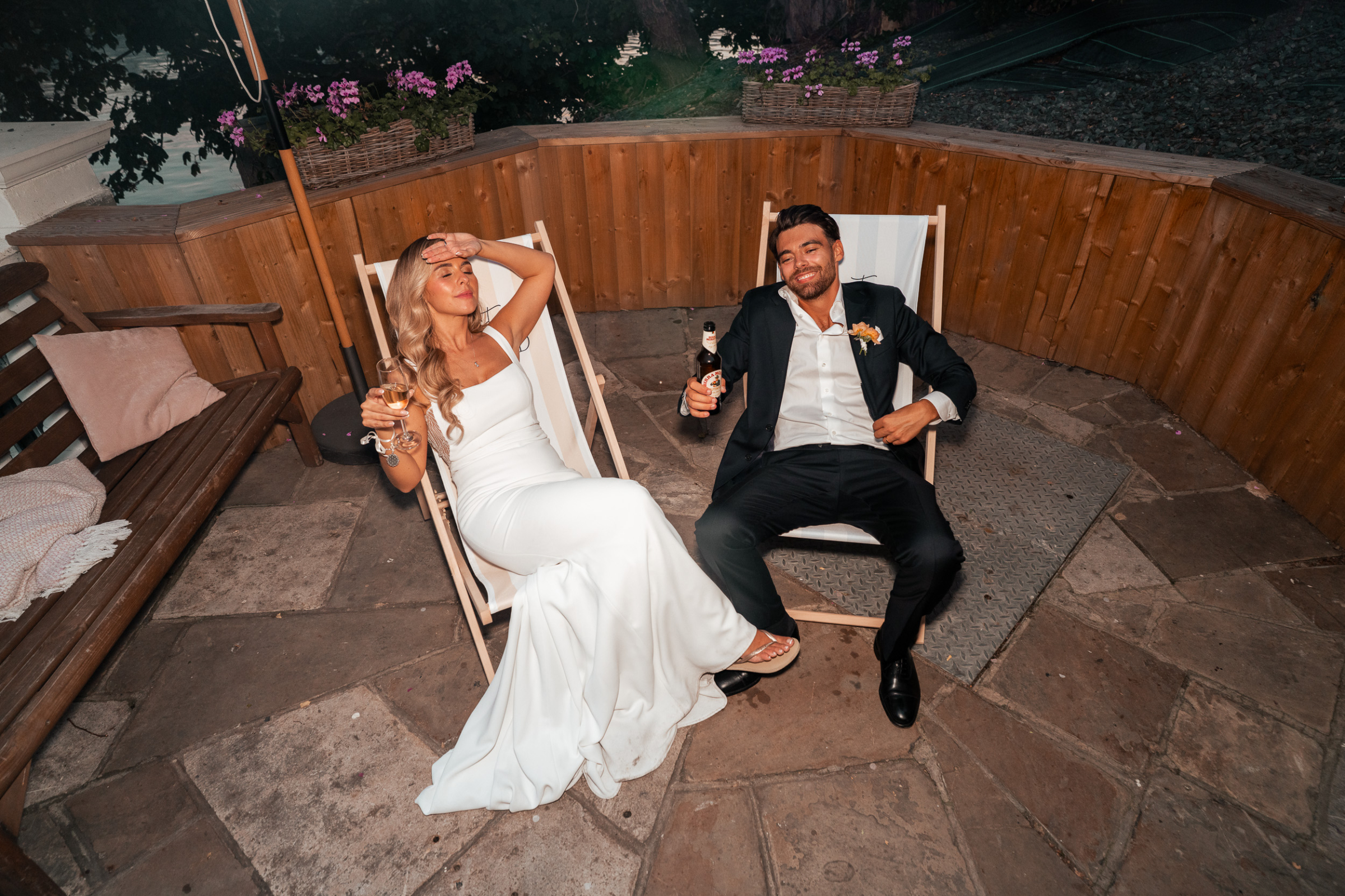 Bride and groom relaxing in deck chairs at the end of their wedding day.