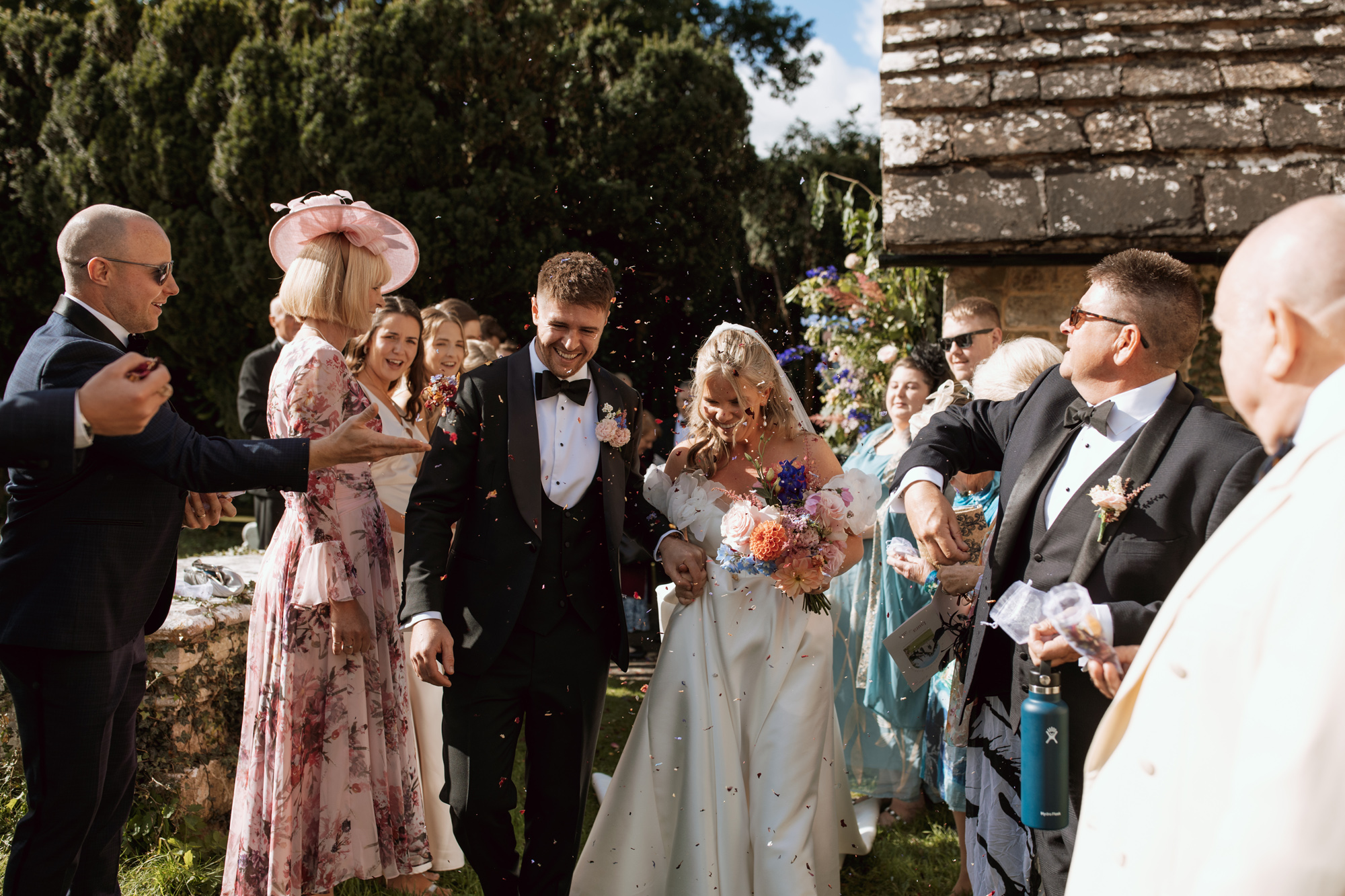 Bride and groom exiting church to a shower of confetti.