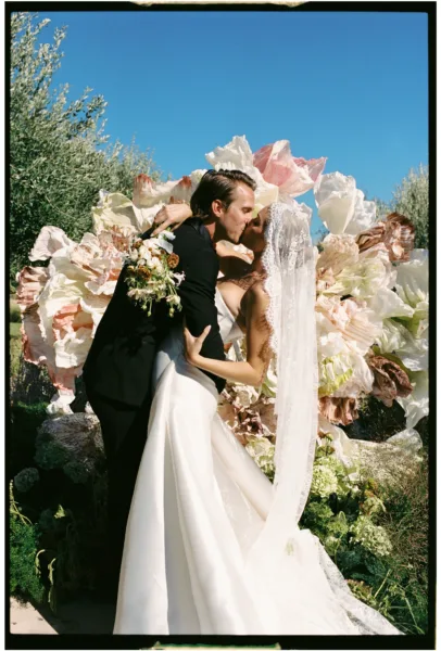 Bride and groom sharing their first kiss in front of a floral ceremony installation in Sicily, Italy.