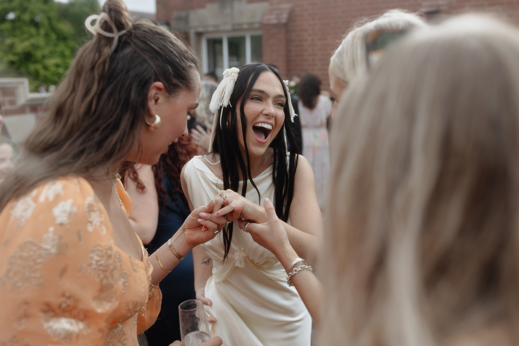 Smiling happy bride wearing a tasseled wedding dress by Paula Nadal and showing wedding guests her ring.
