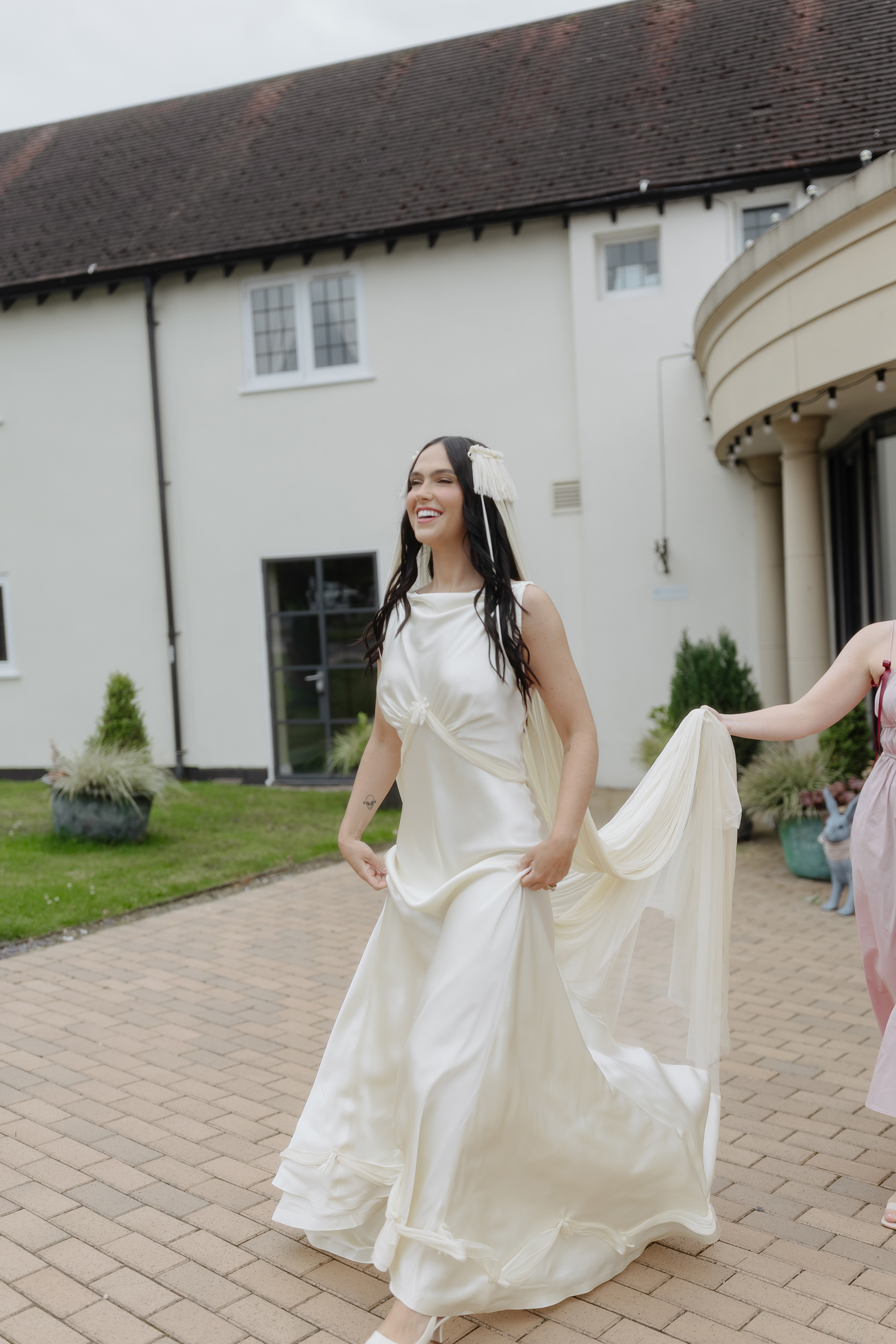 Bride stepping outside in her vintage inspired Paula Nanda wedding dress and fringed tasseled wedding veil.