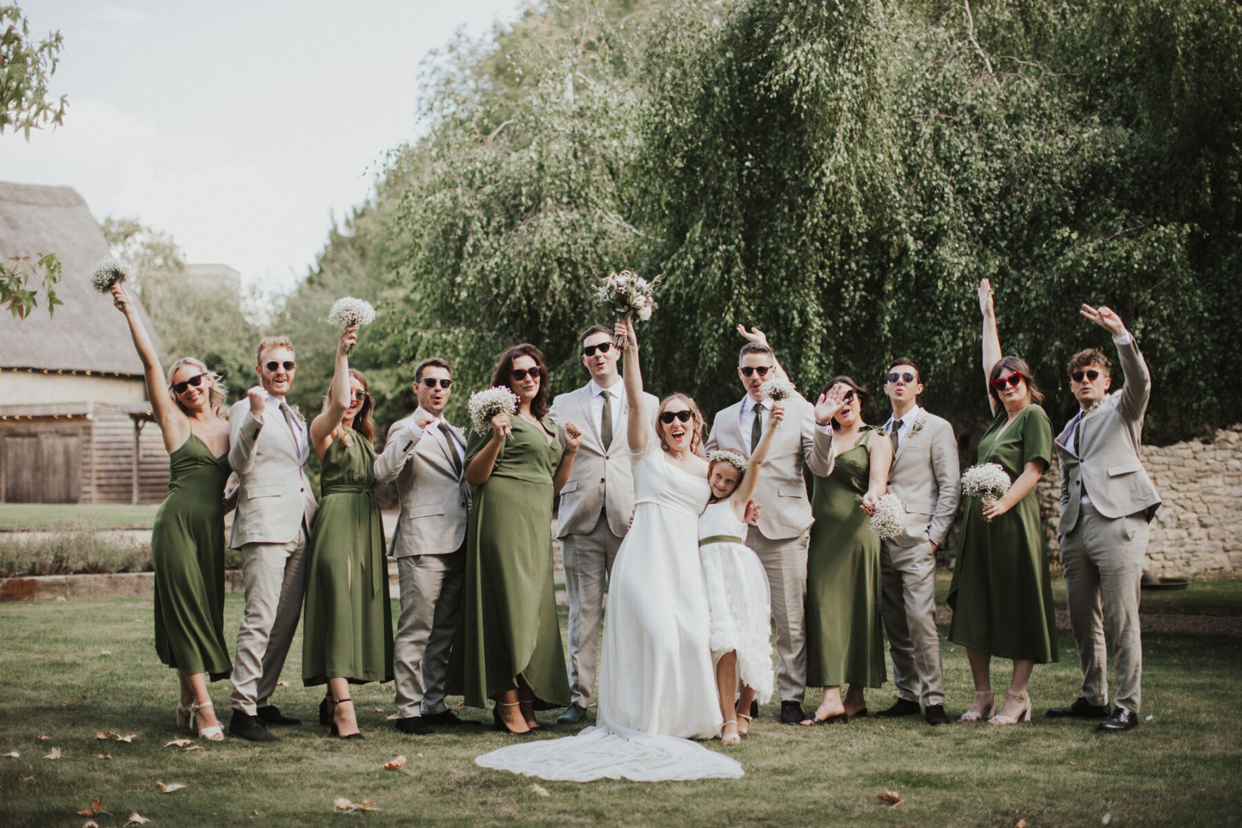 Tythe Barn wedding in Oxfordshire. Bride and groom lined up with the bridesmaids in green dresses.