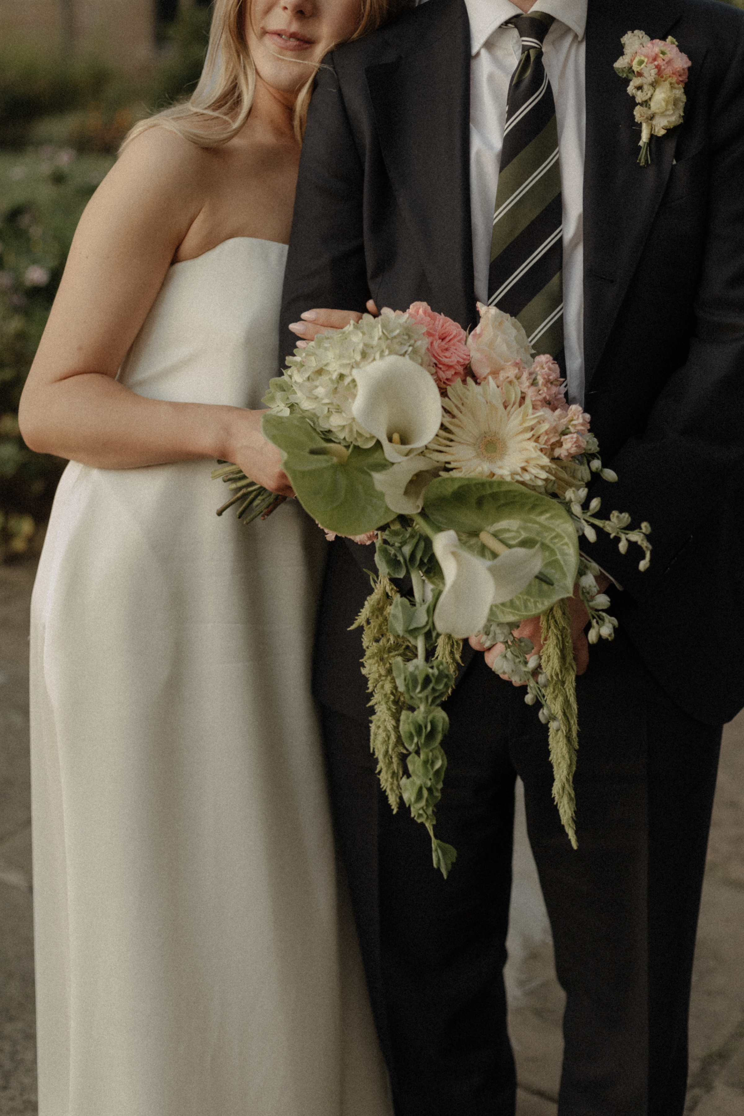 Close up bride wearing a minimalist dress and carrying a large bouquet.