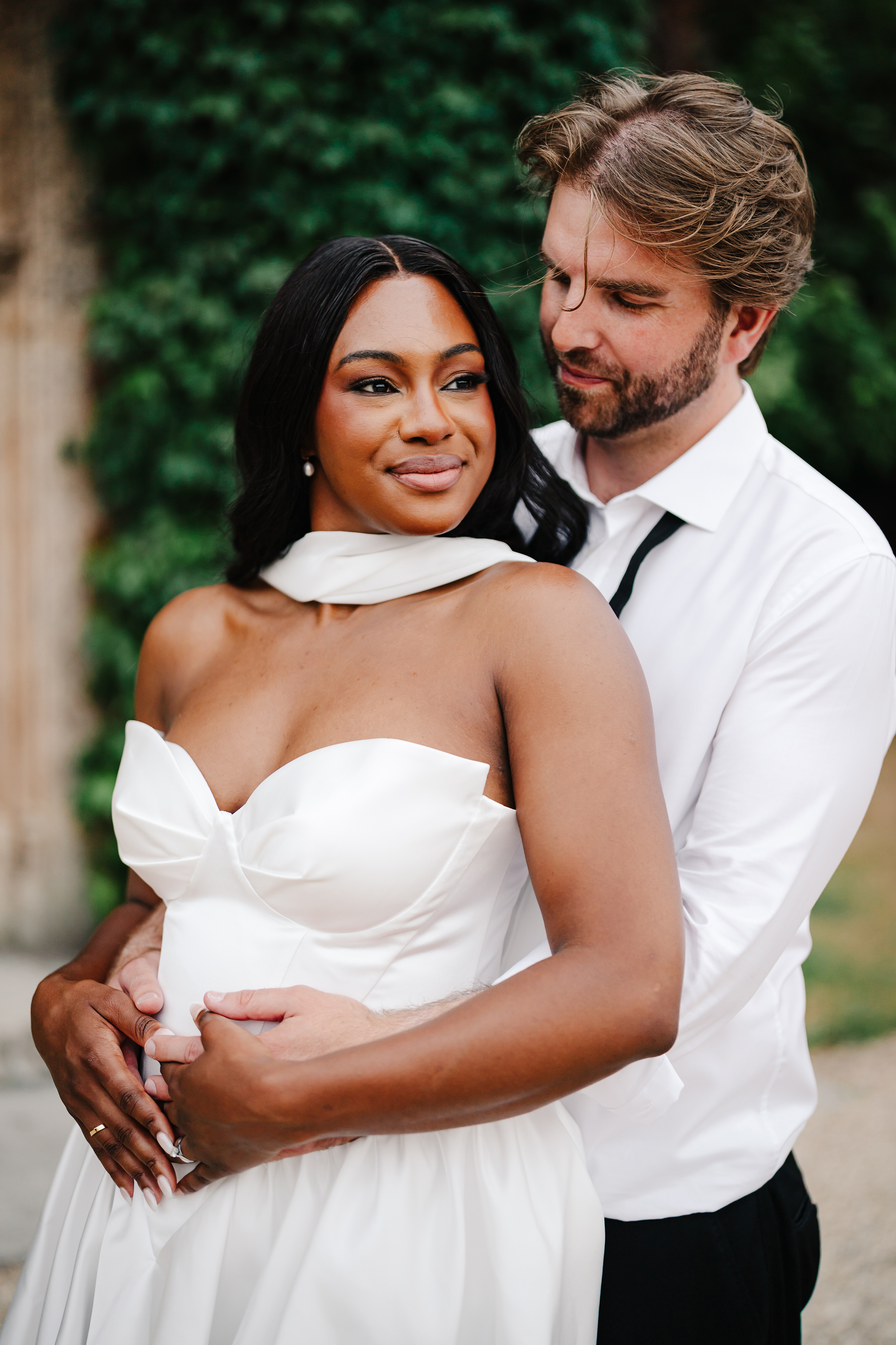 Black bride in a mini wedding dress. Groom with loose bow tie hugging his bride.