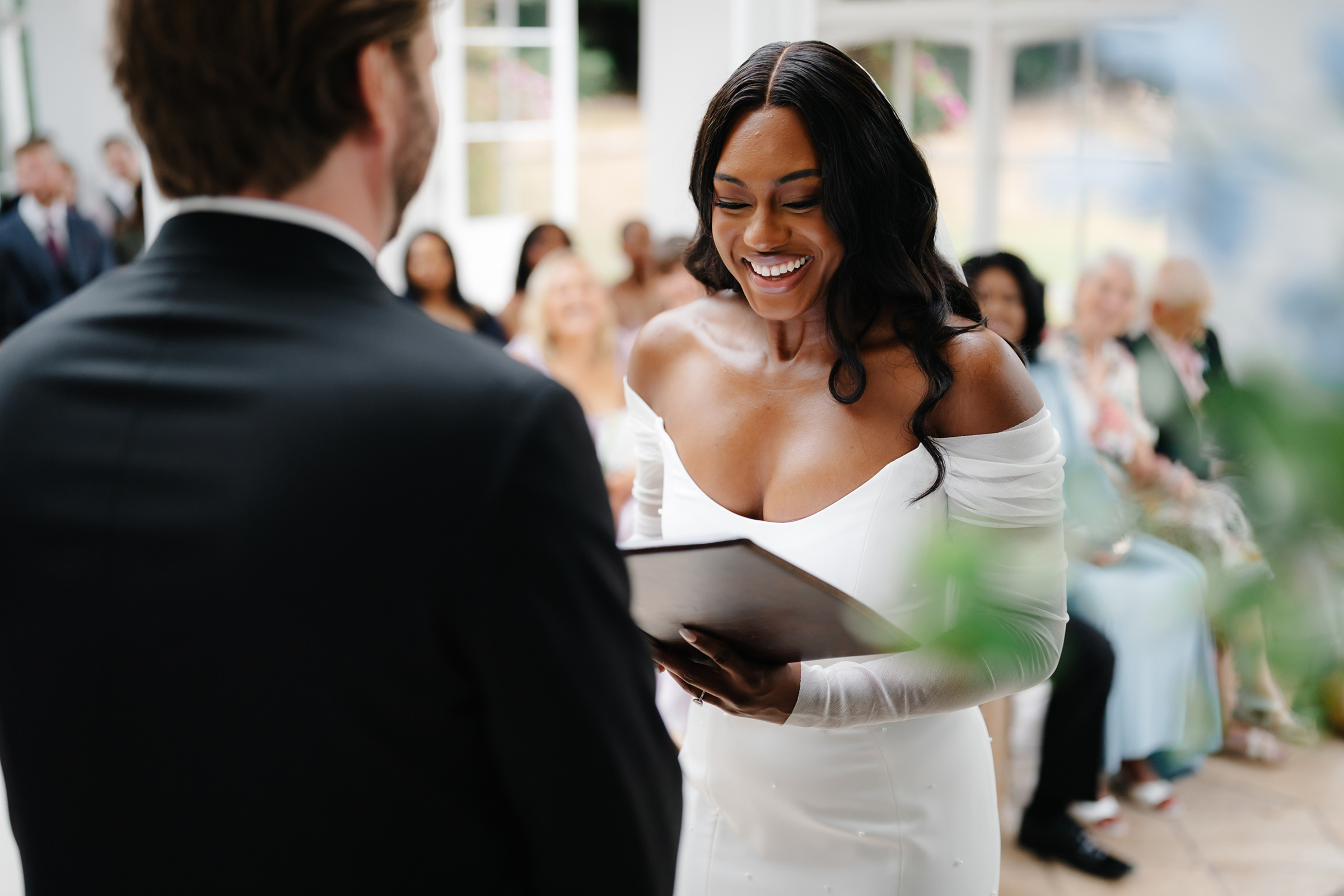Black bride smiling as she reads her vows to her husband at her St Audries Park in Somerset. She wears Bronte by Sarah Seven. Jodie Hurd Photography.