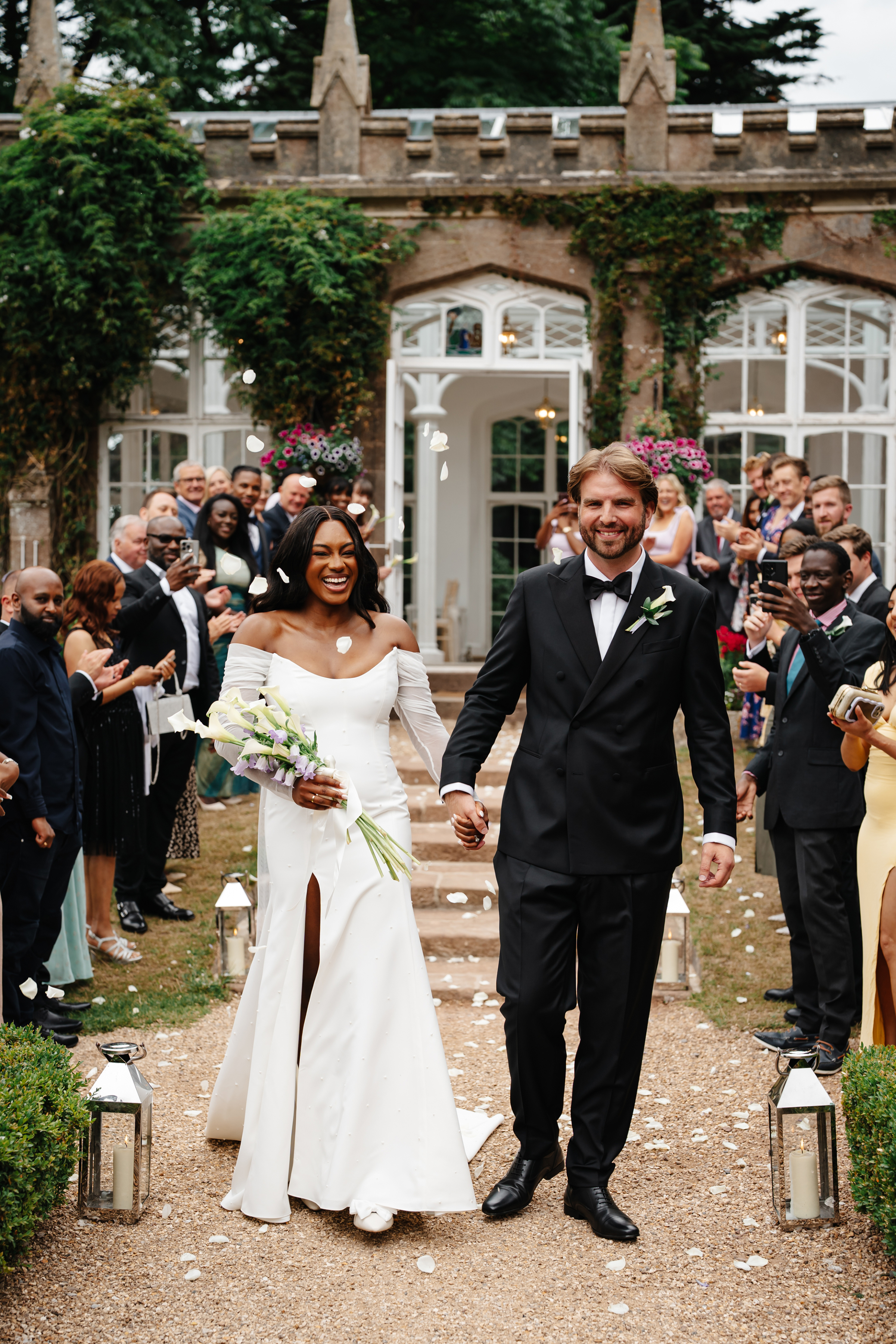 Beautiful Black bride exiting her wedding ceremony at St Audries Park. She wears Bronte by Sarah Seven and carries a bouquet of calla lillies.