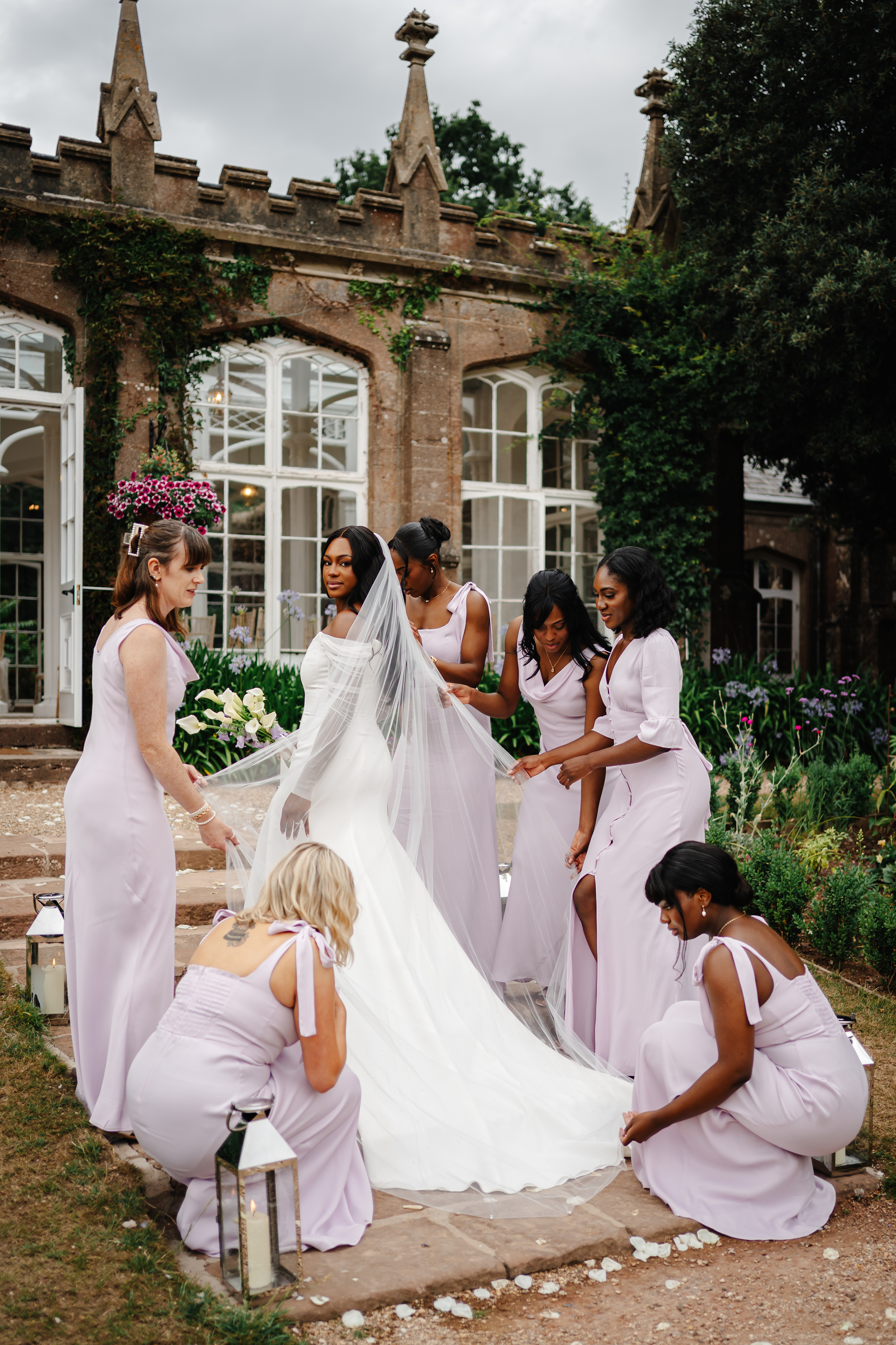 Black bride surrounded by her bridesmaids wearing lilac dresses by Maids To Measure. St Audries Park wedding, Somerset.