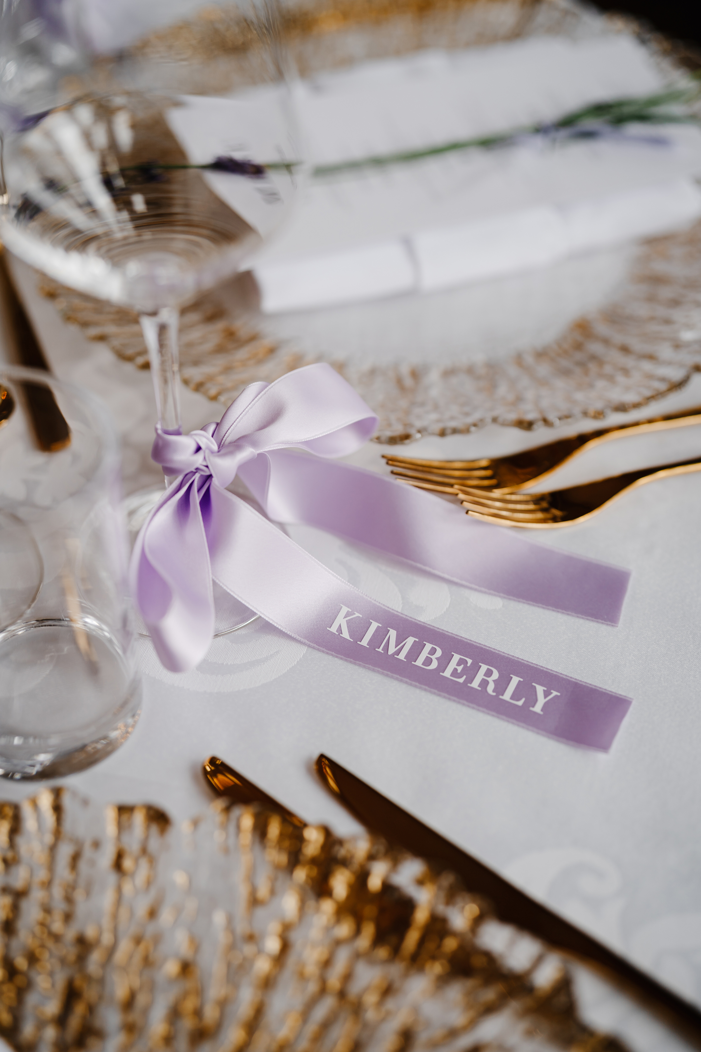 Tall stemmed glass tied with a lilac ribbon anbd the name of the wedding guest.