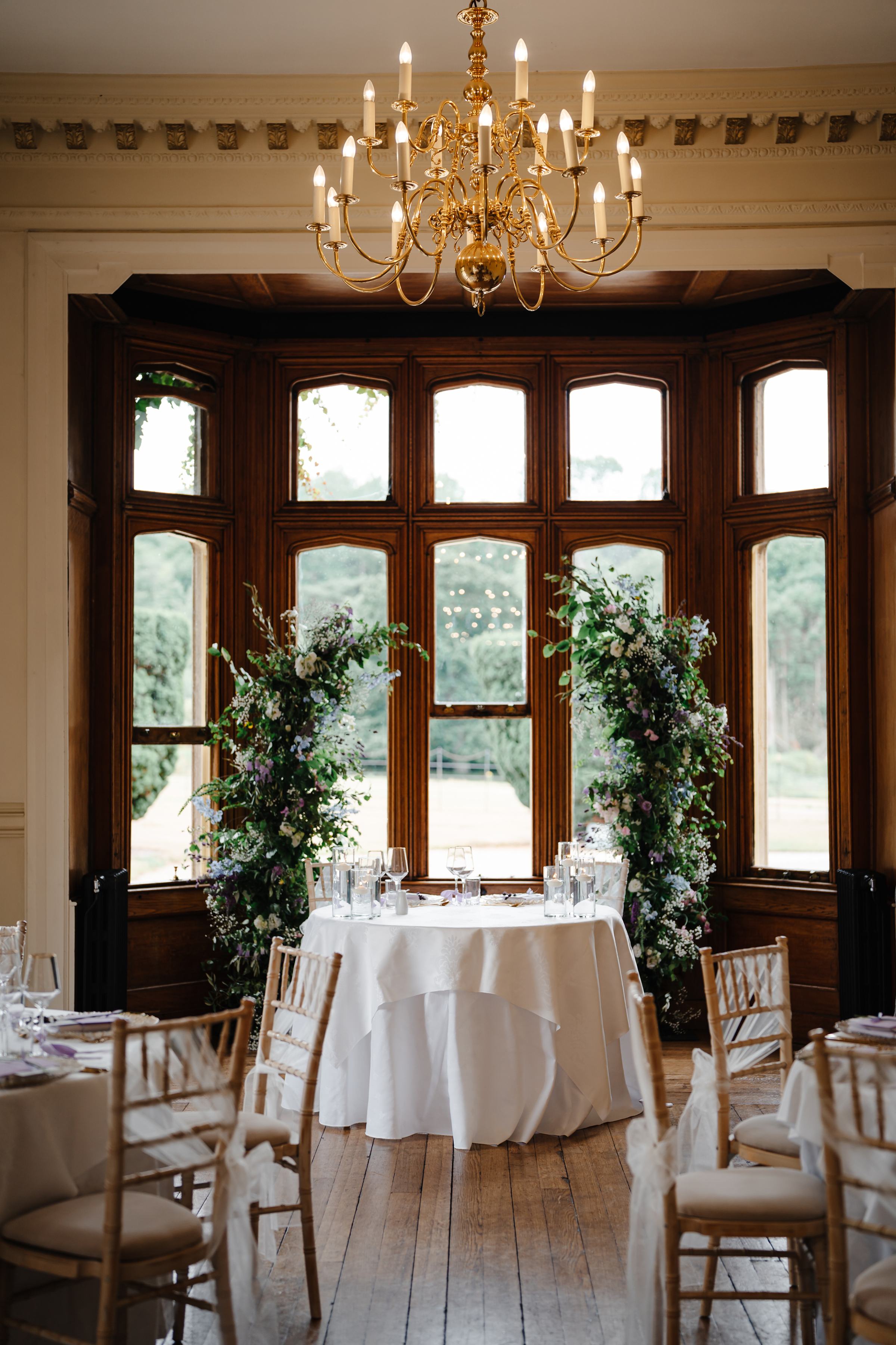 Sweetheart table at a wedding reception at St Audries Park in Somerset. The couple have relocated the broken floral arch from the ceremony behind them. 