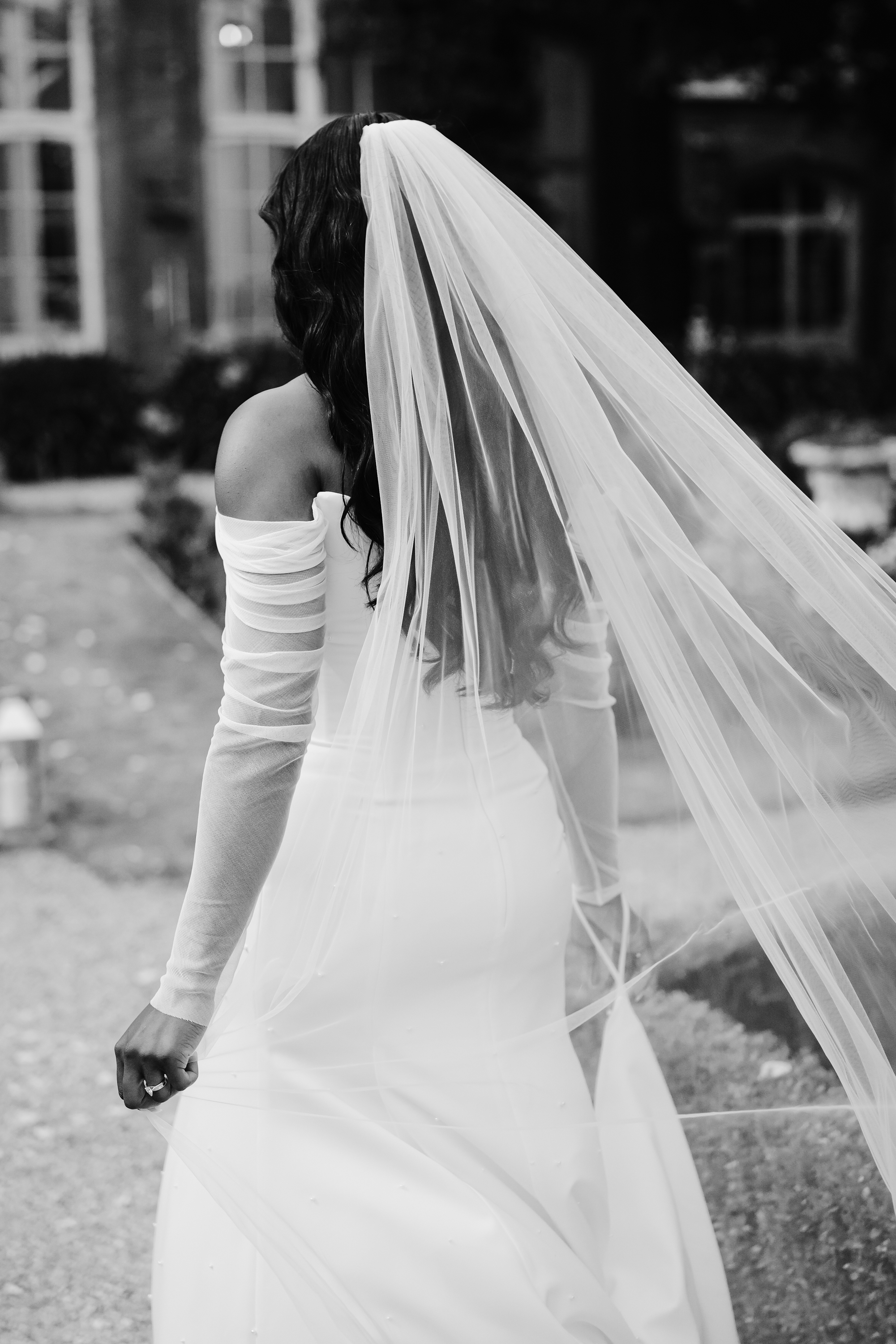 Photography of the back of a bride walking away in her Bronte dress by Sarah Seven and long simple tulle veil.
