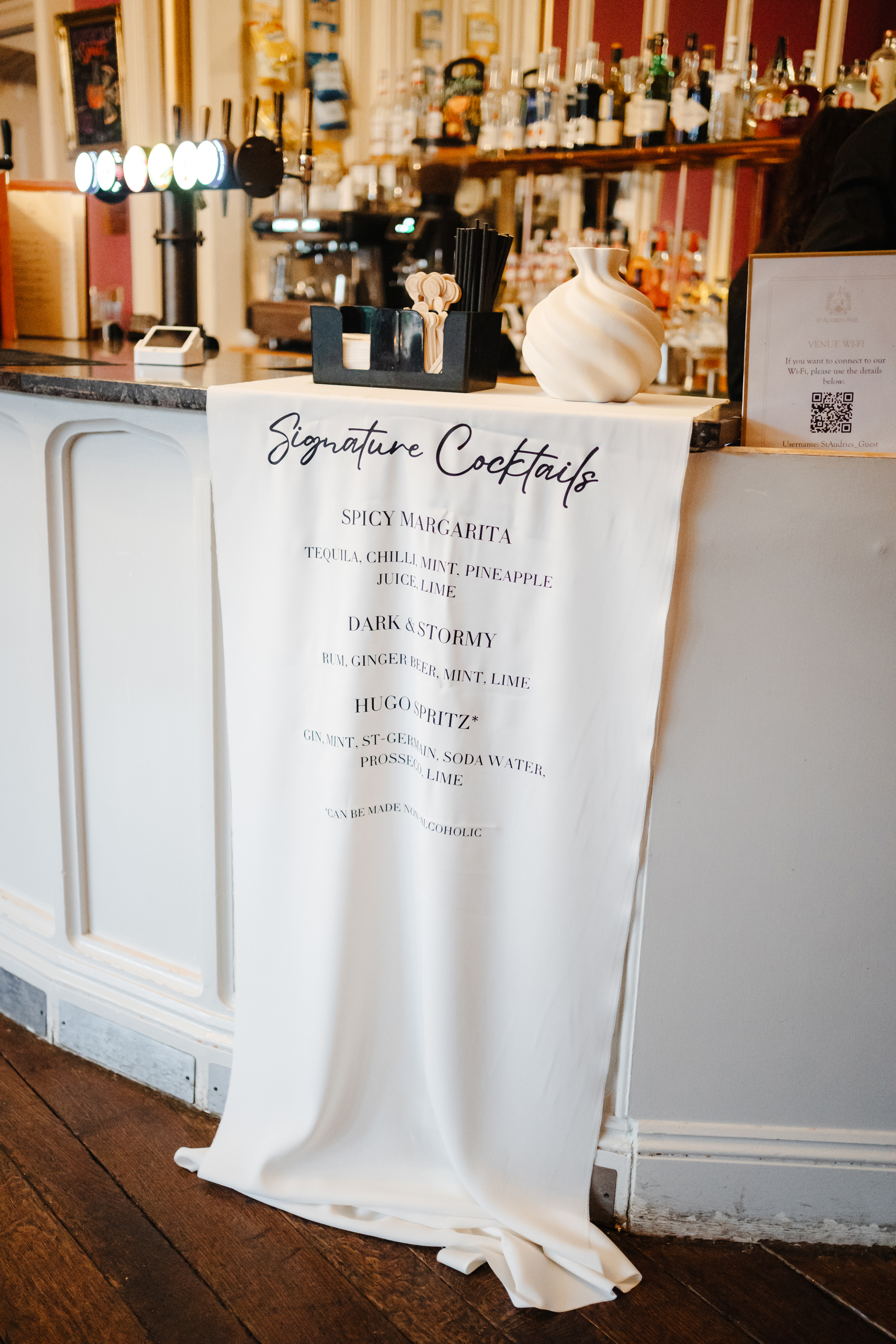 Signature cocktails menu printed. on fabric and draped over the bar.