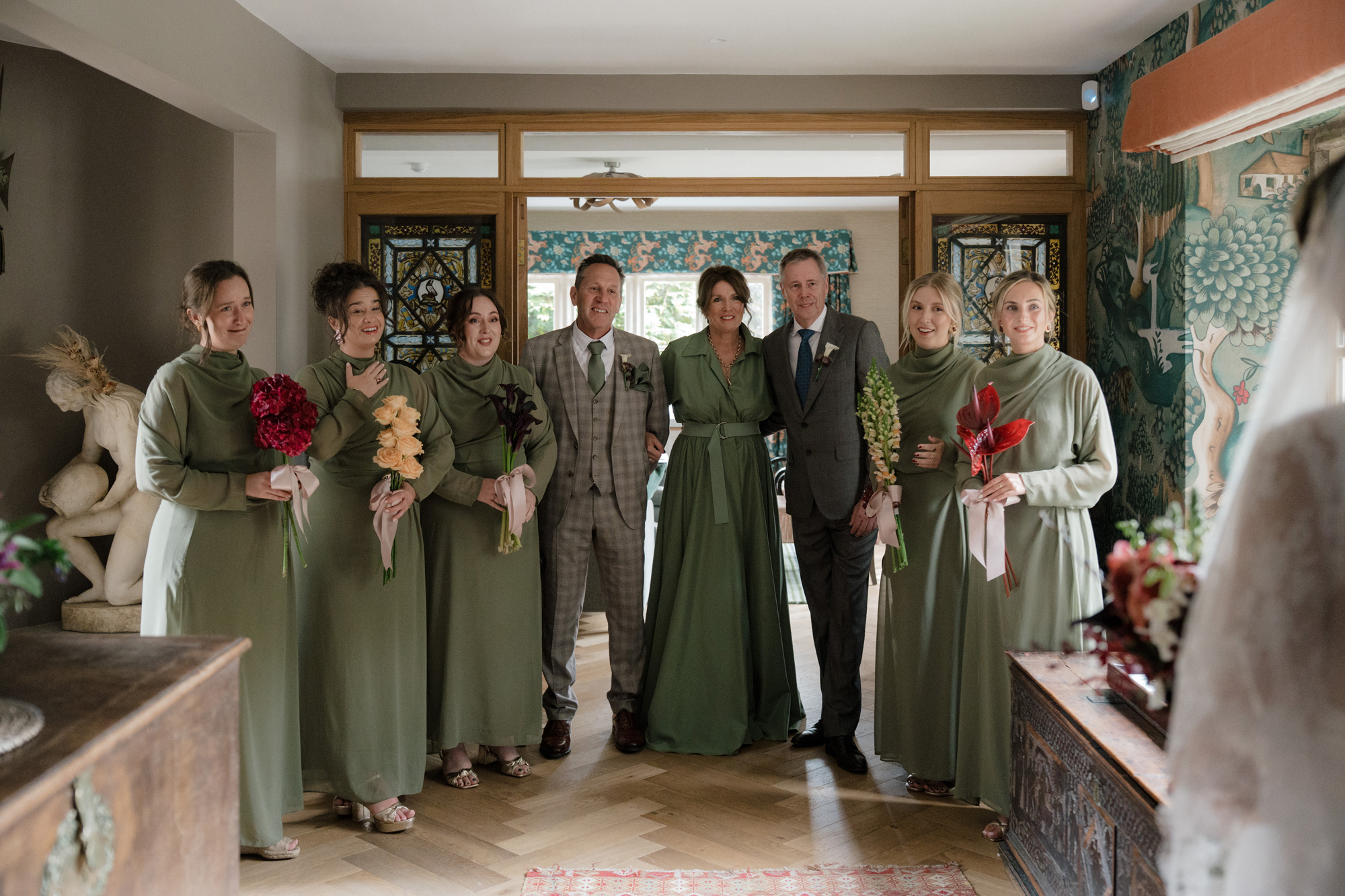 Bridesmaids in olive green long sleeved dresses at Gulliver's Hall, a Unique Home Stays wedding venue in The Cotswolds.