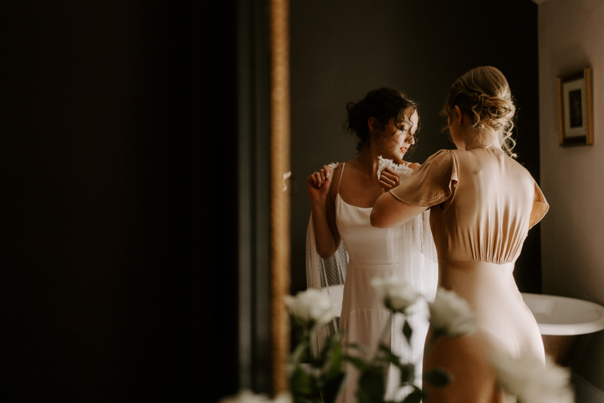 Bridesmaid helping the bride get into her dress at Low Hall The Lakes rustic English country wedding venue in The Lake District.