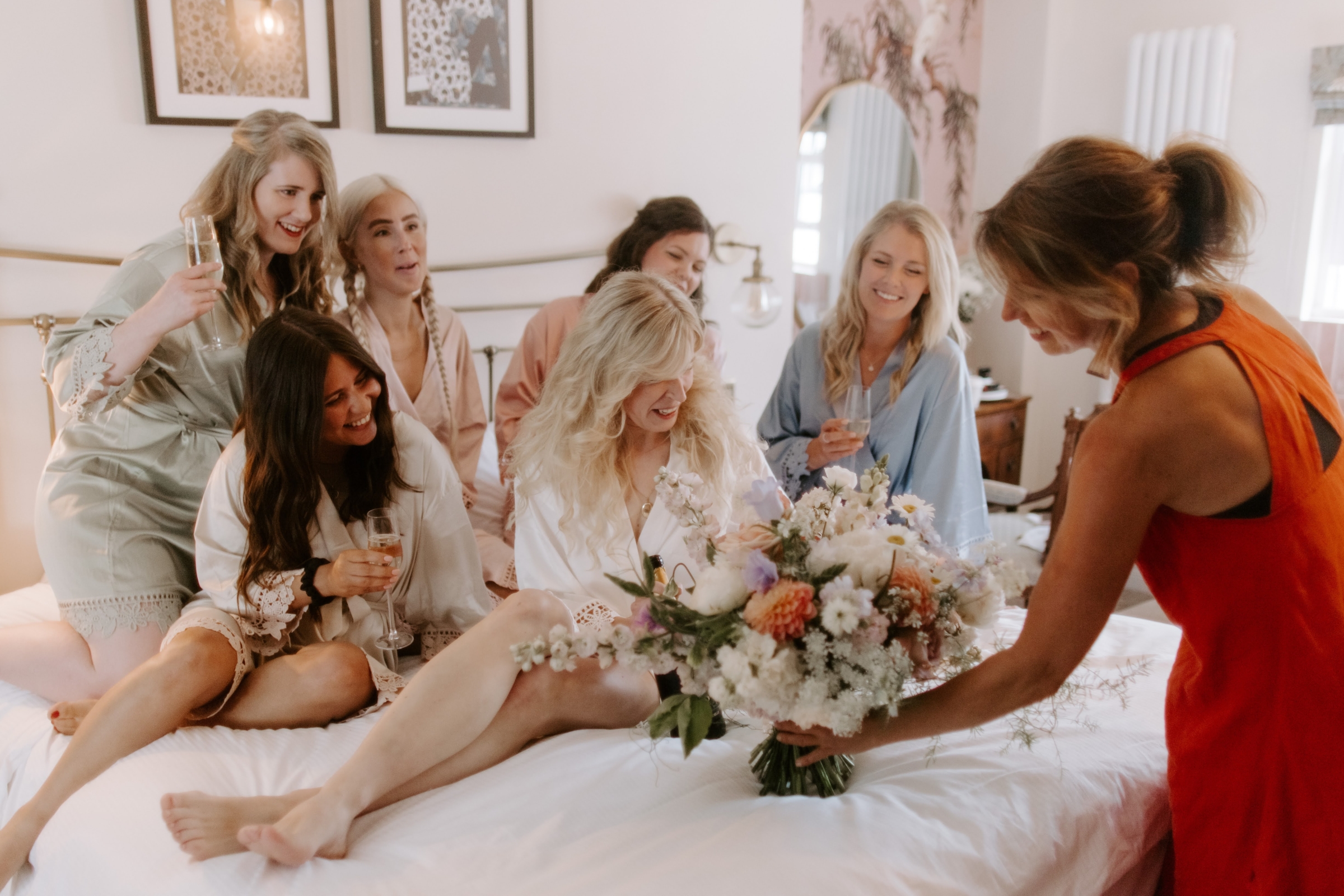 Bride getting ready sat on the bed with her bridesmaids at Low Hall The Lakes rustic English country wedding venue in The Lake District.