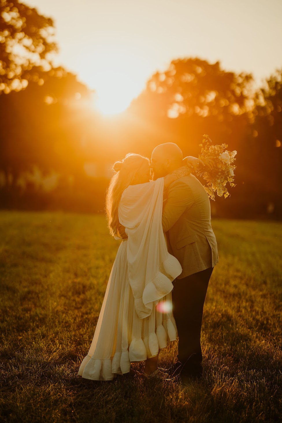 Sublime golden hour shot of bride and groom kissing in a field. Wedding at Low Hall The Lakes in The Lake District.