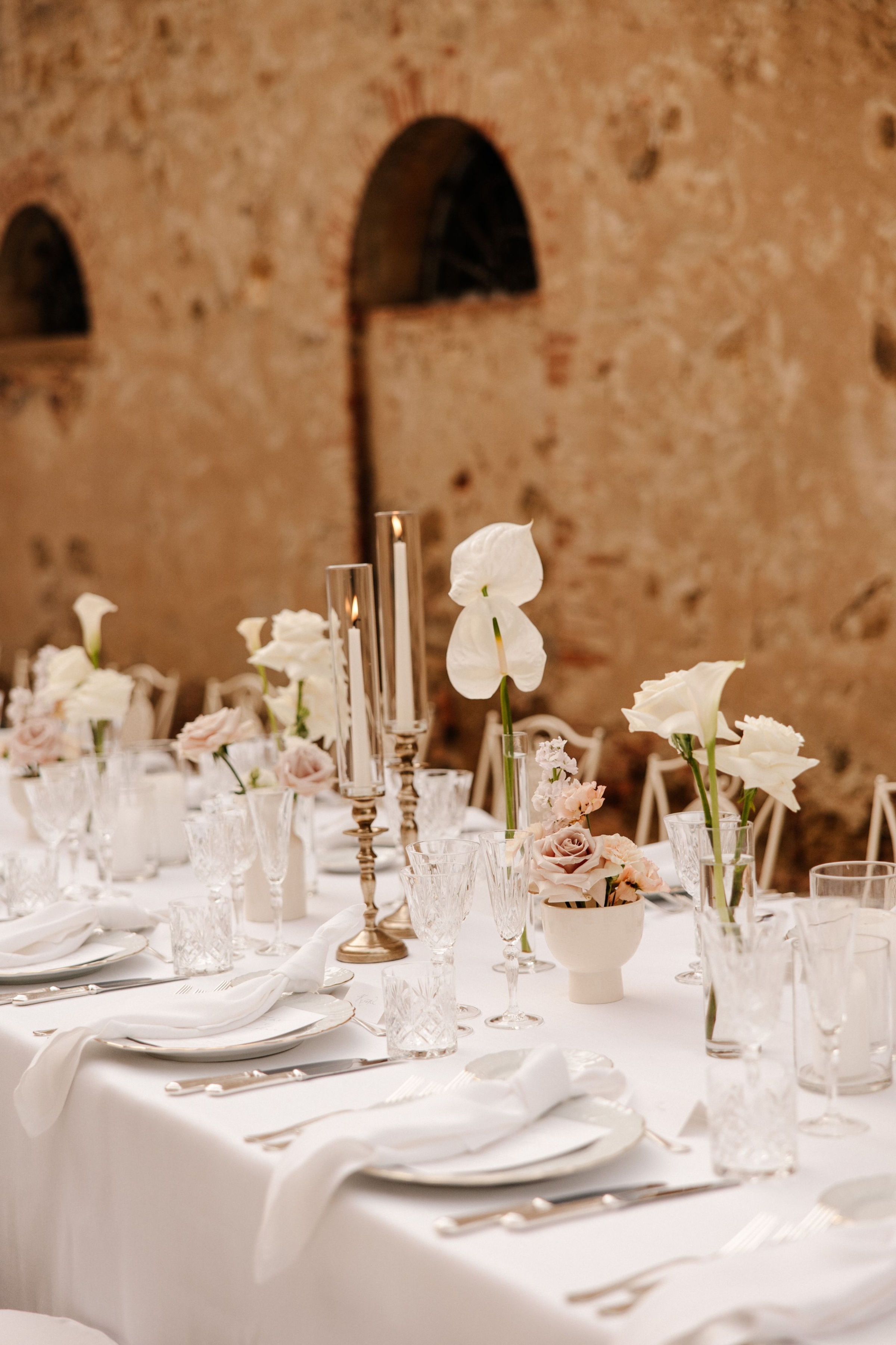 Wedding Borgo Sant Ambrogio Tuscany Italy 79 - A Modern, Romantic Destination Wedding at Borgo Sant Ambrogio in Tuscany Elegant white and neutral table decor wedding at Borgo Sant Ambrogio in Tuscany, Italy. White table linen, pale candles inside hurricane glasses vases, white orchids and white tableware and napkins.