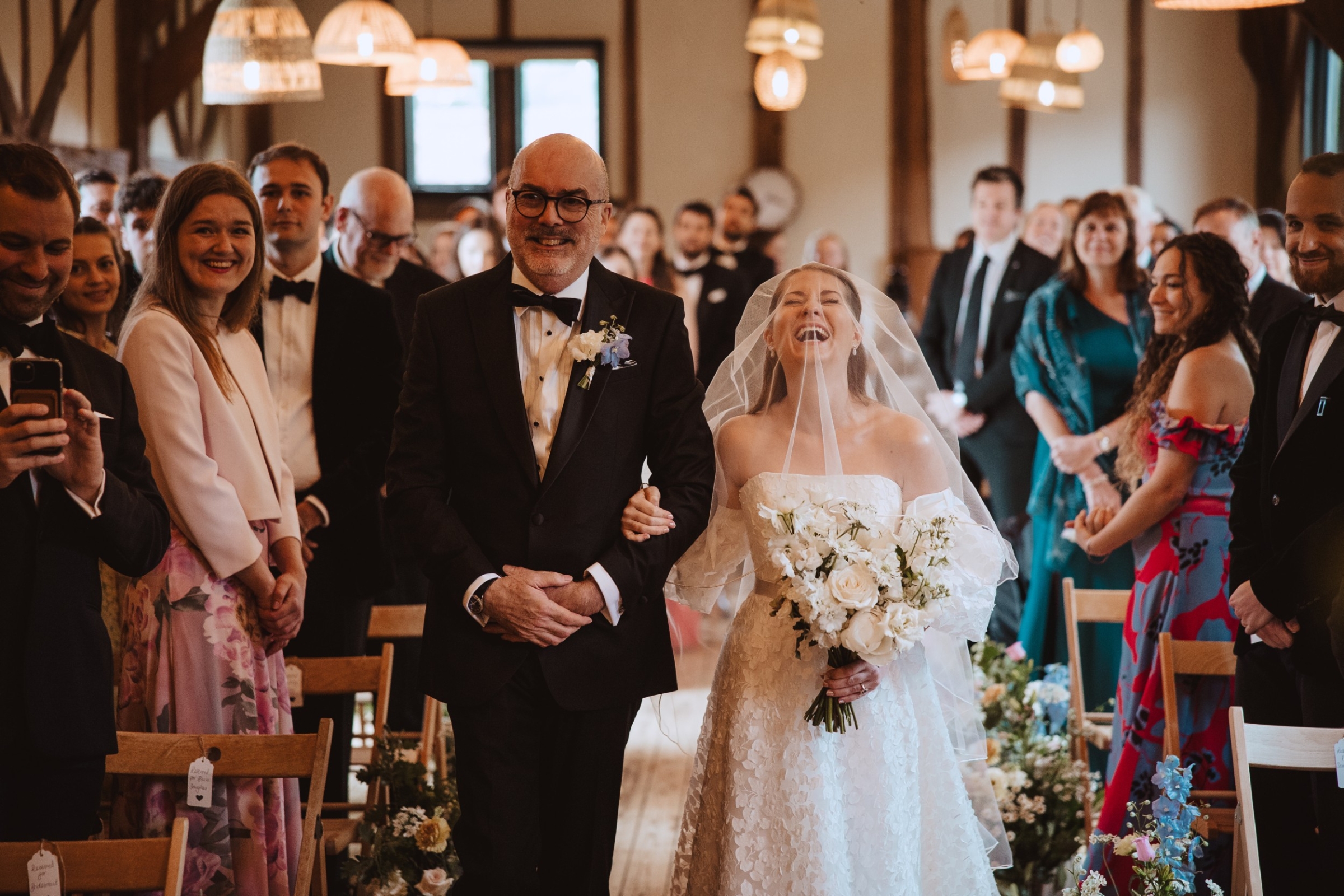 Bore Place Wedding Sassi Holford bride 59 - Hatty & Ben’s Nancy Meyers Inspired Black Tie Wedding at Bore Place, Kent Father of the bride in black tie walking his daughter down the aisle - they are both giggling.