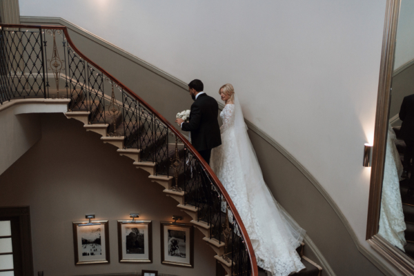 Married couple walking up grand staircase in Manor House venue