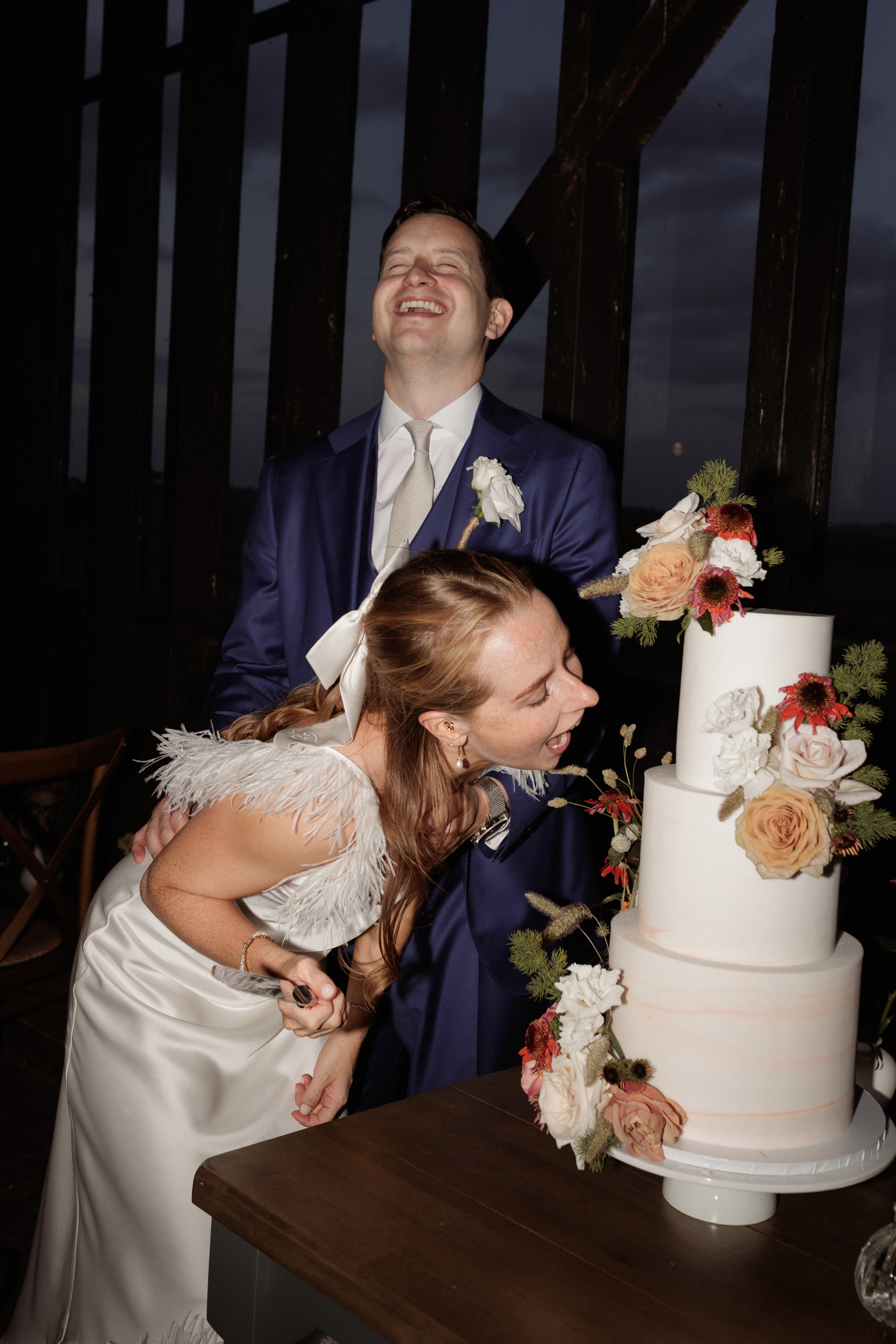 A Summer Wedding at Elmley Nature Reserve with Halfpenny London 95 Cheeky shot of bride leaning in to take a bite out of her wedding cake.