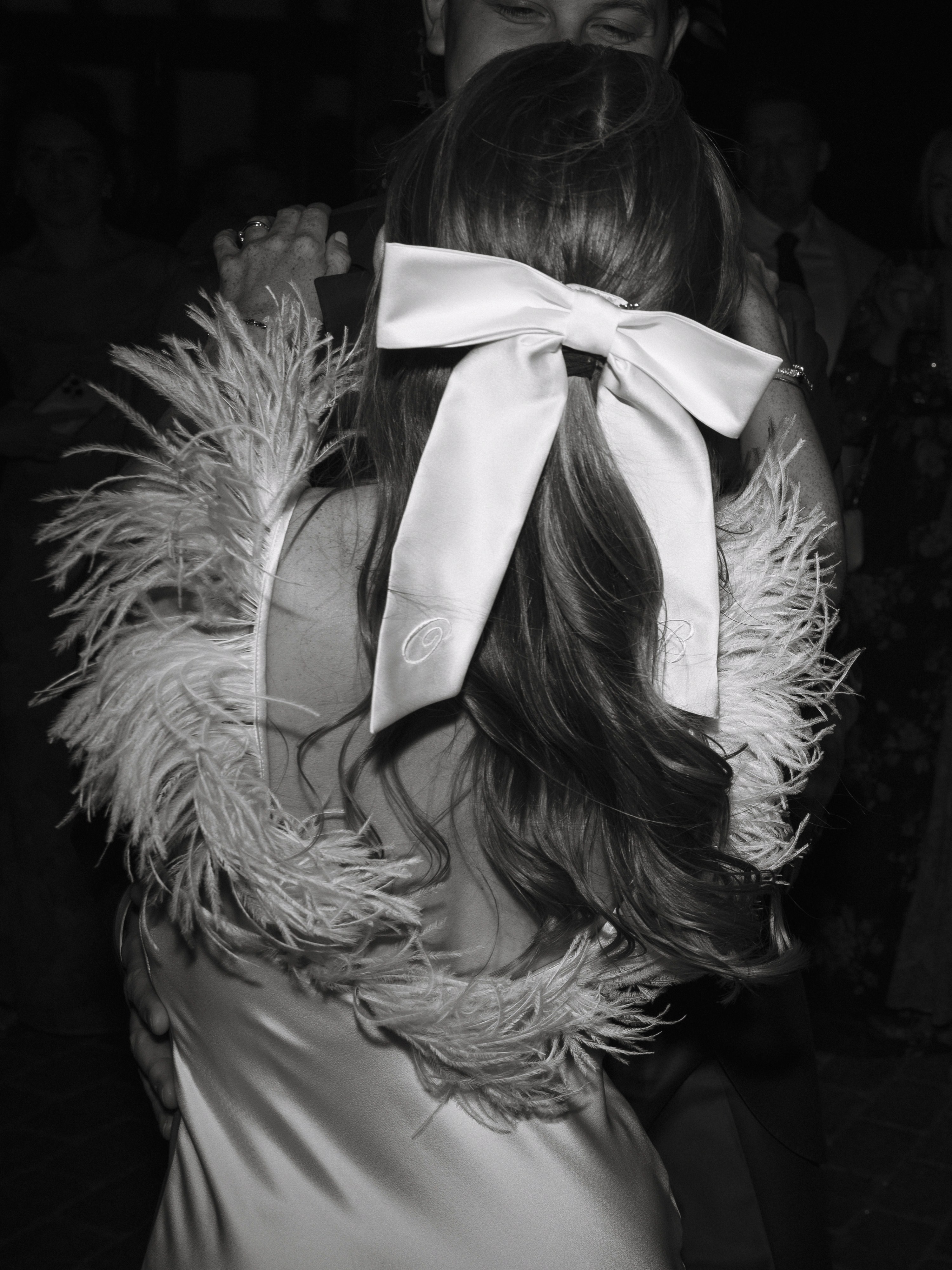 A Summer Wedding at Elmley Nature Reserve with Halfpenny London 110 Bride wearing chunky a Gigi & Olive embroidered bow in her hair. Her dress with ostrich feather shoulders is by Halfpenny London.