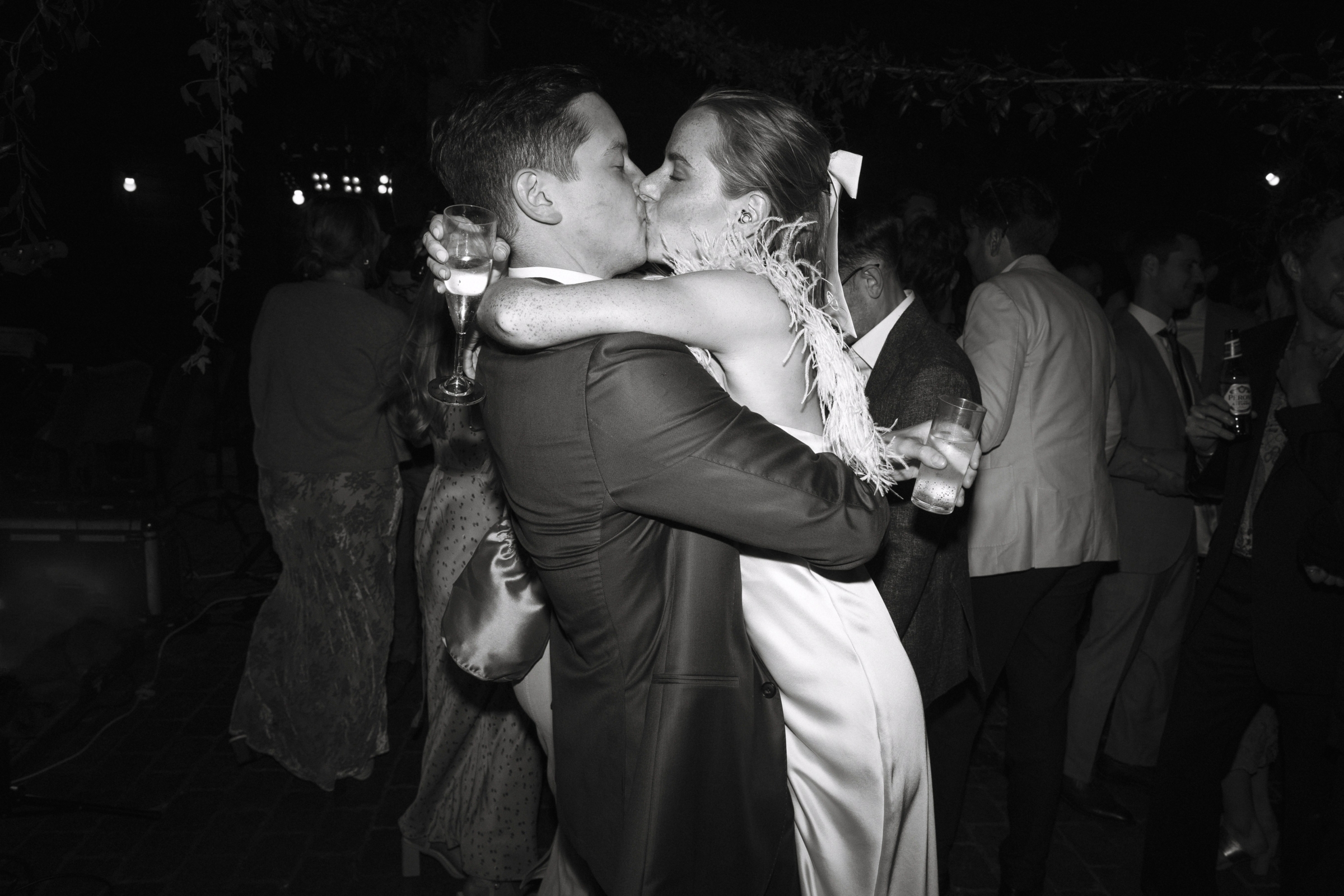 A Summer Wedding at Elmley Nature Reserve with Halfpenny London 114 Bride in an ostrich feather dress by Halfpenny London being gently lifted off the dance floor, whilst kissing her groom. Elmley Nature Reserve wedding venue, Kent.