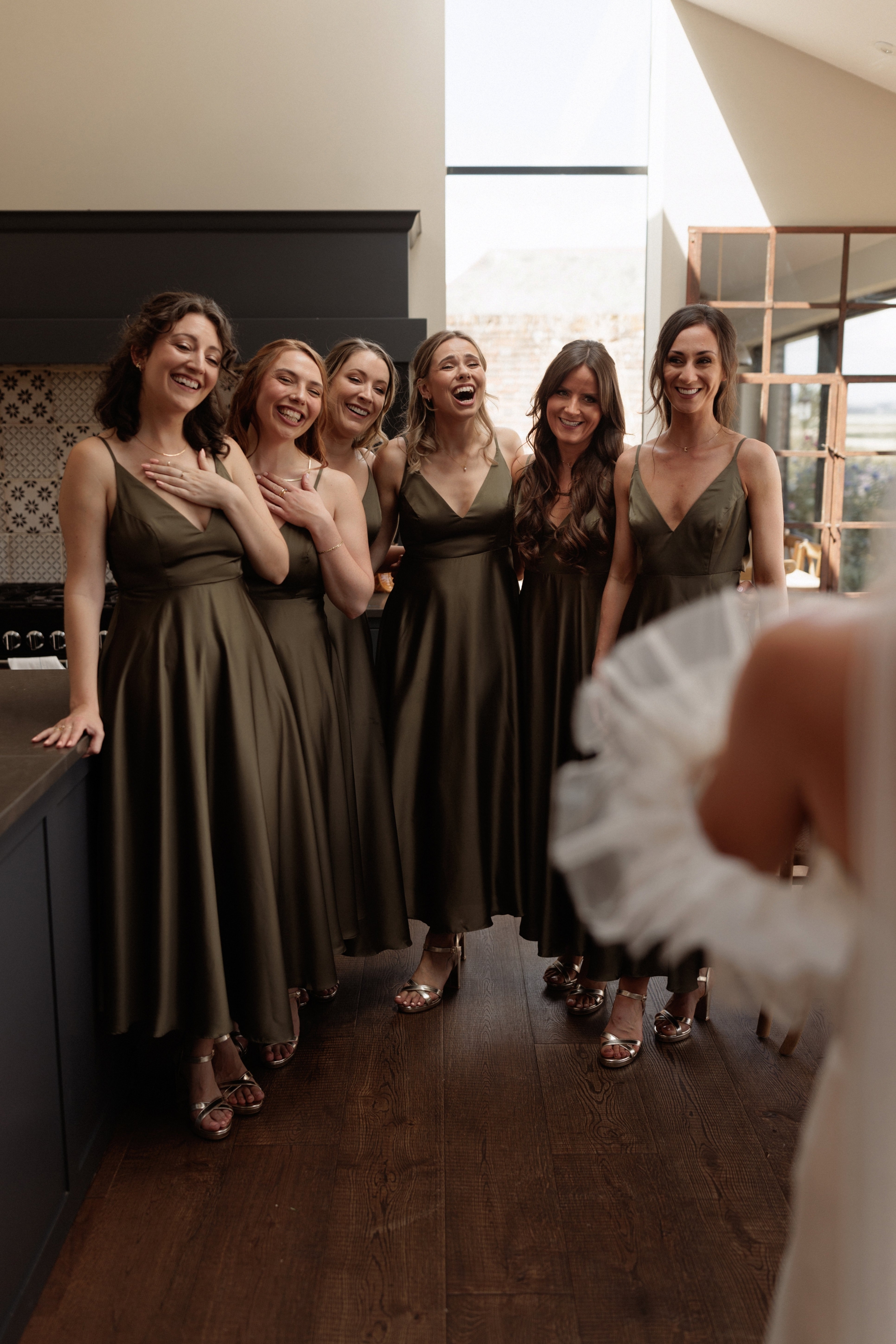 A Summer Wedding at Elmley Nature Reserve with Halfpenny London 48 Bridesmaids in olive dresses from ASOS admiring the bride in her Halfpenny London dress.