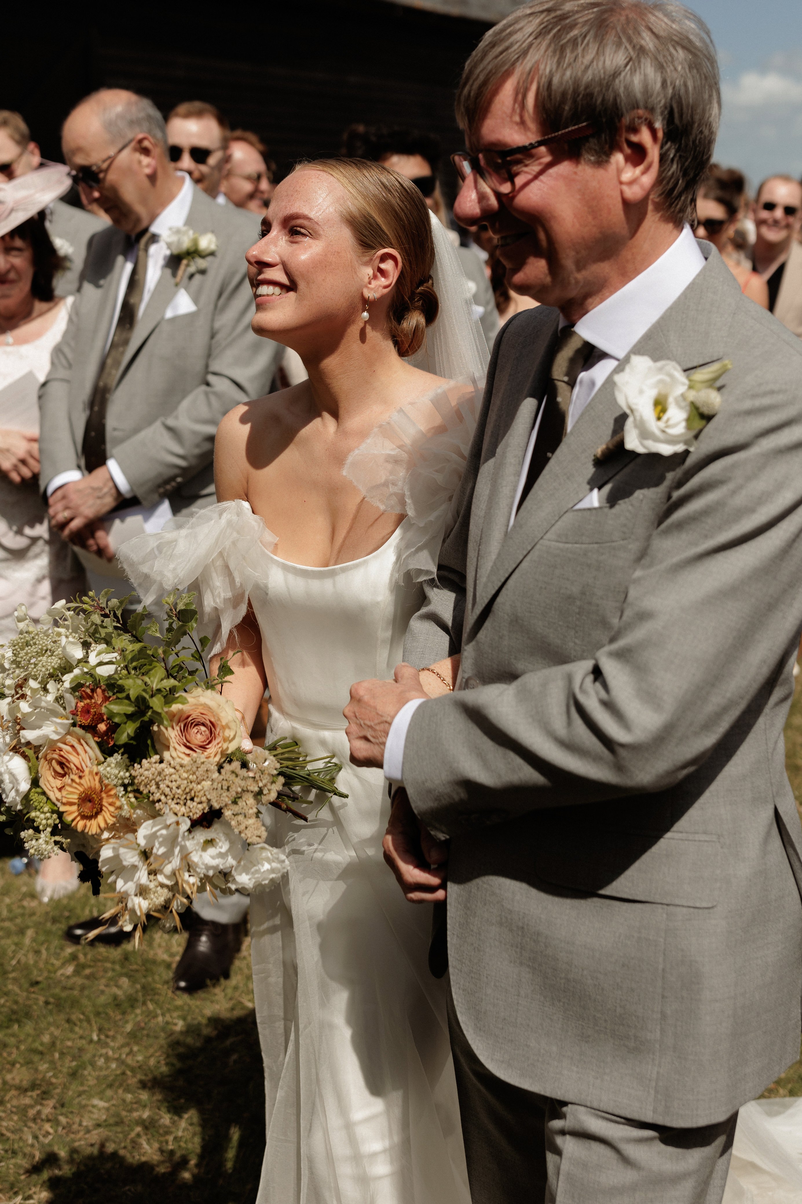 A Summer Wedding at Elmley Nature Reserve with Halfpenny London 52 Elmley Nature Reserve wedding - the bride is being accompanied by he father down the aisle.