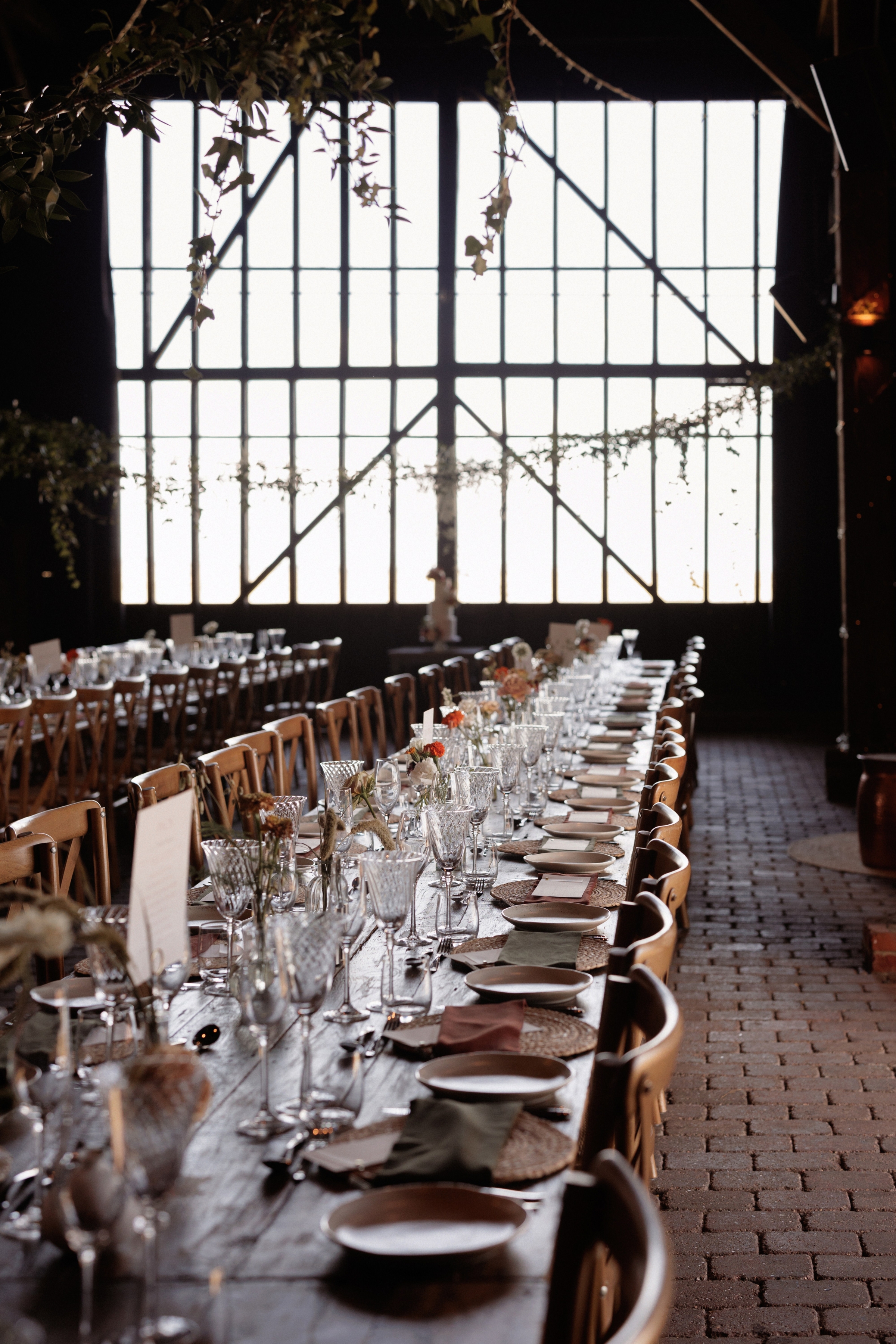 A Summer Wedding at Elmley Nature Reserve with Halfpenny London 91 Inside the barn at Elmley Nature Reserve wedding venue in Kent. Long wooden trestle tables and cross back chairs await the wedding guests.