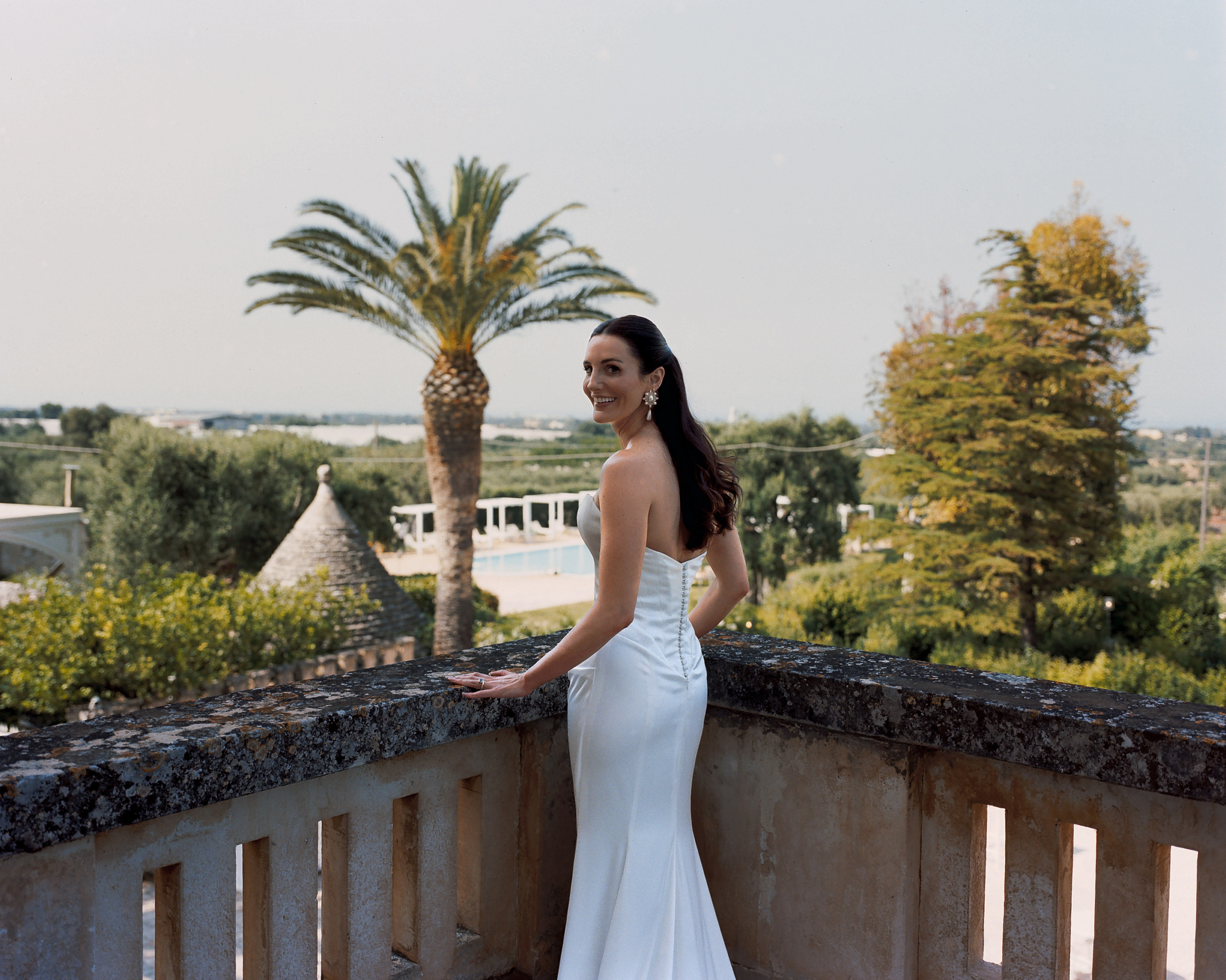 Will & Heather's Romantic Wedding in Puglia Inspired by Classic Italian Design 58 Bride wearing a Lihi Hod wedding dress, stood on the balcony at Masseria Salamina wedding venue in Puglia, Italy.