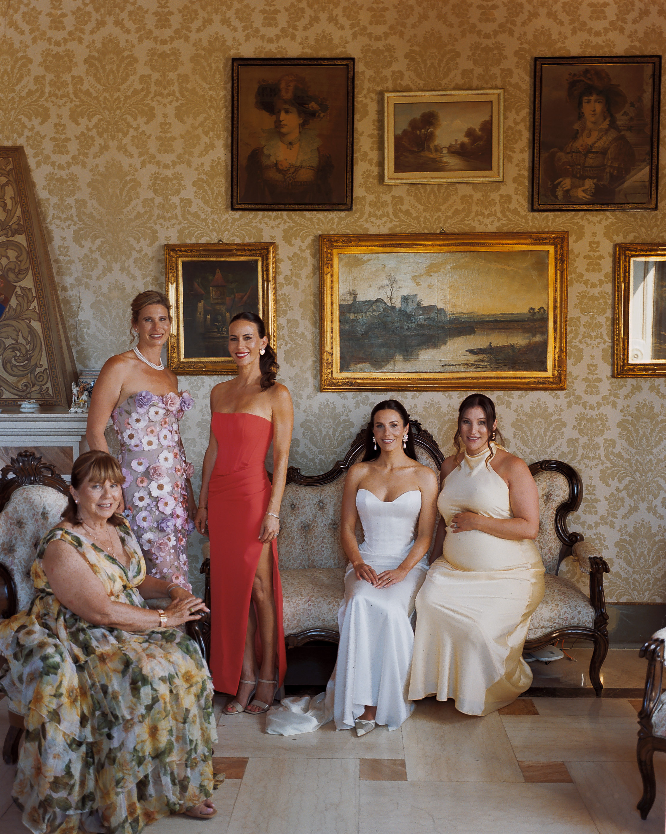 Will & Heather's Romantic Wedding in Puglia Inspired by Classic Italian Design 57 Beautifully posed image of bride wearing a Lihi Hod wedding dress for her wedding in Puglia, Italy, seated whilst surrounded by her bridesmaids in various different dresses.
