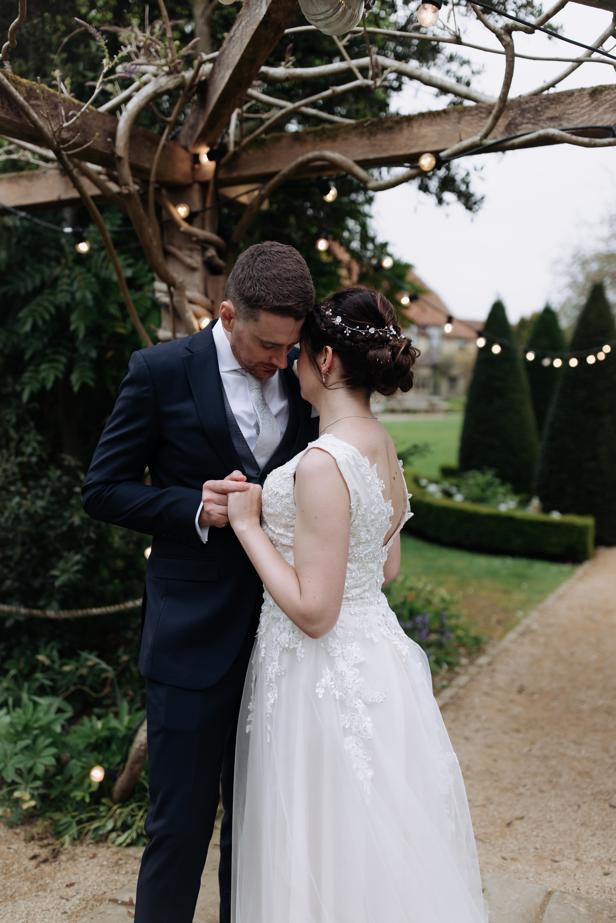 Bride and groom embracing in the gardens at Tythe, an Oxfordshire barn wedding venue. 