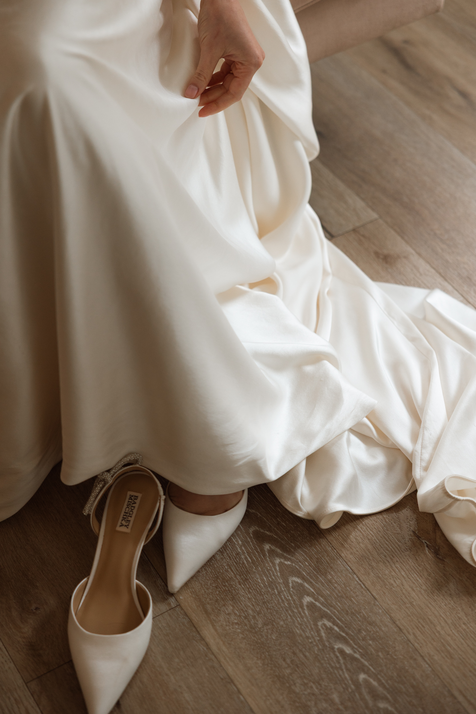 Vivienne Westwood bride Pinewood Weddings Events MA USA 14 - Emma Wore Vivienne Westwood for Her Joyful, Equality Inspired Summer Wedding Close up shot of bride putting her flat heeled Badgley Mischka shoes on with her Vivienne Westwood wedding dress.