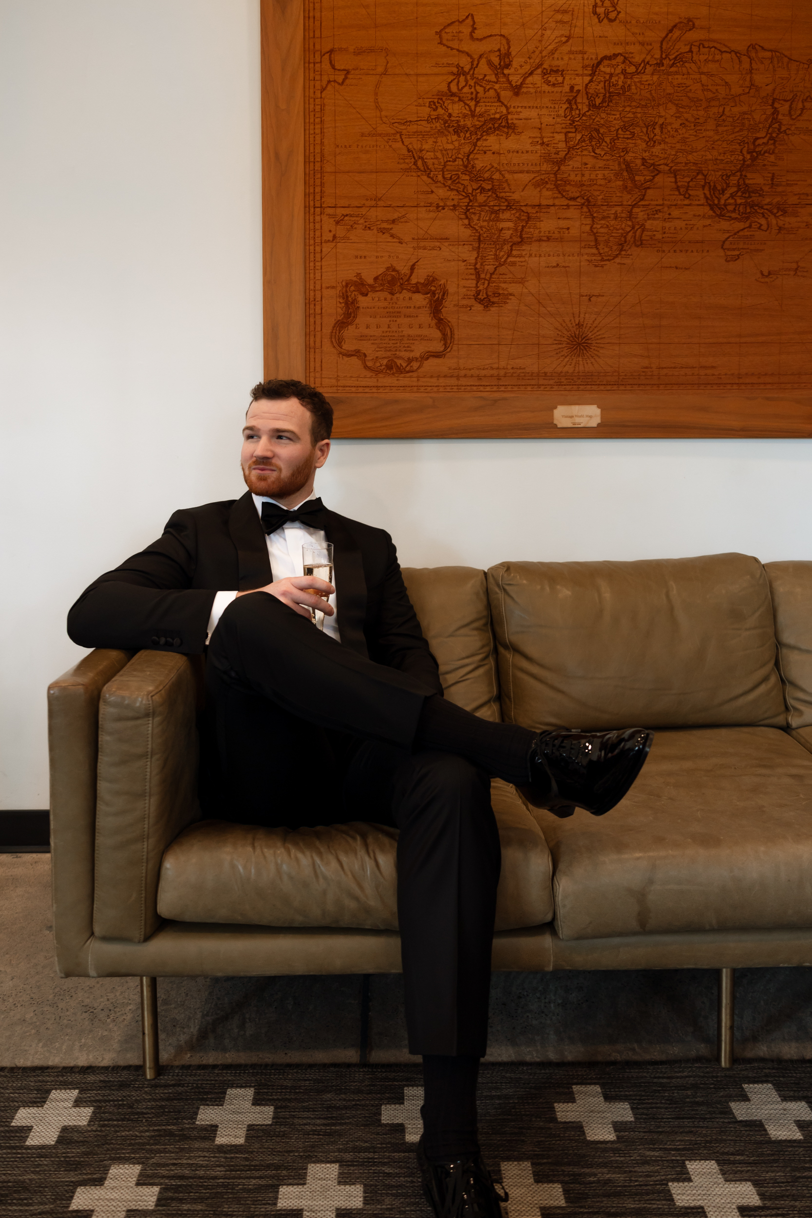 Vivienne Westwood bride Pinewood Weddings Events MA USA 18 - Emma Wore Vivienne Westwood for Her Joyful, Equality Inspired Summer Wedding Groom in black tie reclining comfortably on the sofa with a glass of champagne.