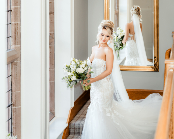 Bride holding bouquet with mirror reflection on staircase - elegant fine-art wedding portrait by Calini Weddings.