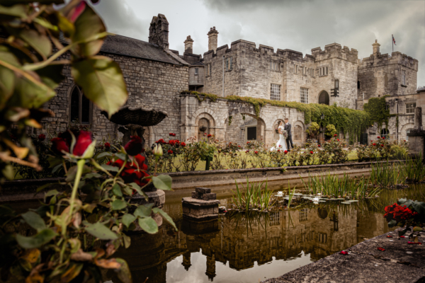 Romantic wedding photography at Hazlewood Castle Yorkshire - couple surrounded by roses and stone architecture captured by Calini Weddings.