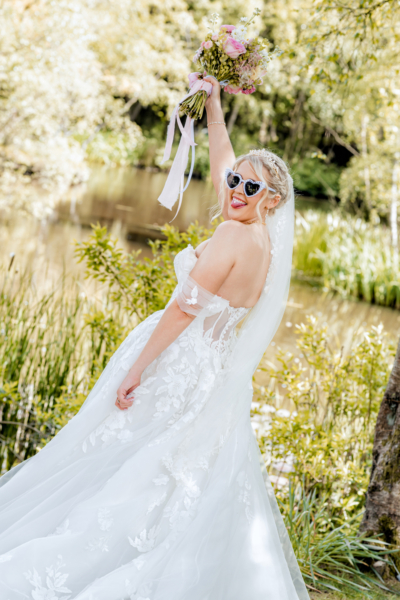 Playful bride outdoors with bouquet and sunglasses - modern editorial Yorkshire wedding photography by Calini Weddings.