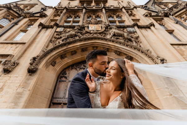 Couple sharing romantic moment under grand Oxford architecture – fine-art editorial wedding photography by Calini Weddings.