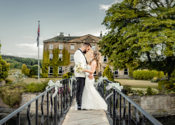 Bride and groom embracing on Waterton Park bridge - elegant Yorkshire wedding photography by Calini Weddings.