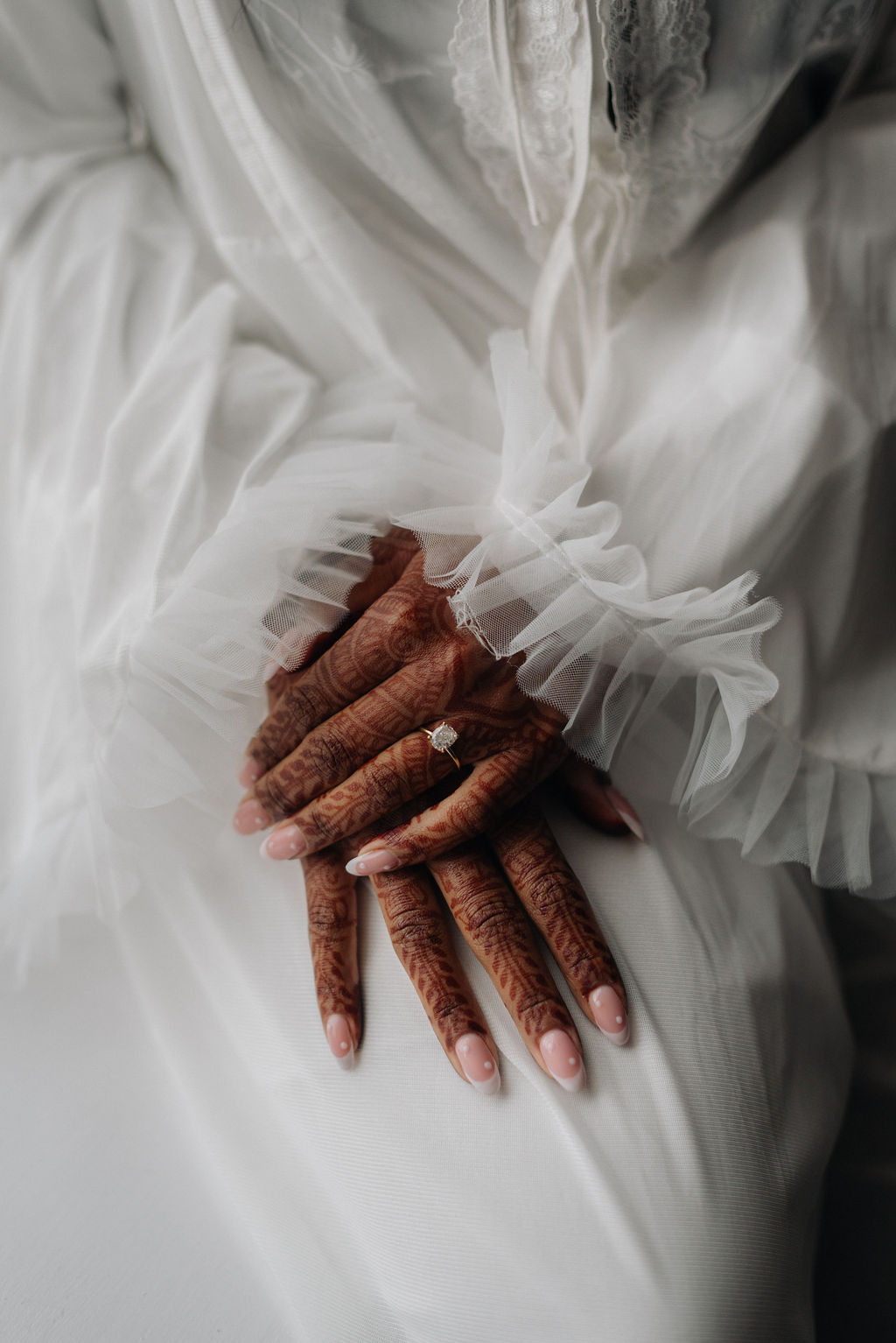 Close up shot of a Black bride with henna tattoos on her hand. She wears frilly nightwear as she gets ready.
